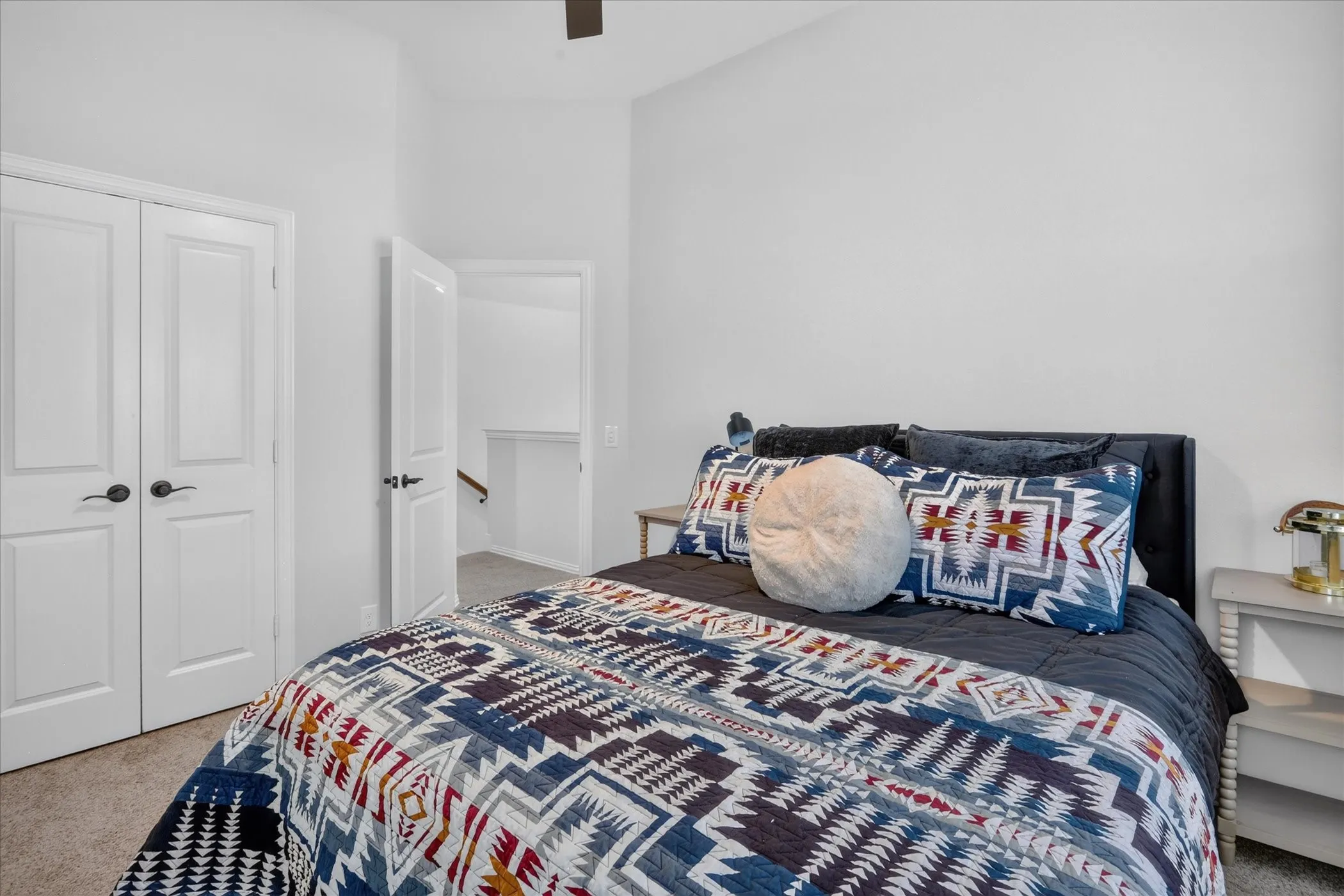 Carpeted bedroom with a vaulted ceiling, presenting a built-in closet with double panel doors and dark hardware