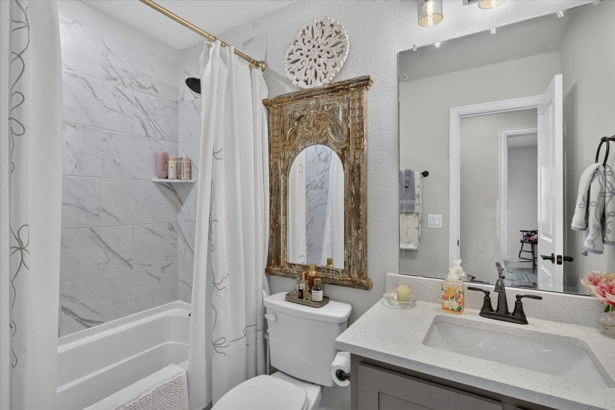 Bathroom featuring a white subway tile shower, built-in shower shelf, and a gold-finish shower rod