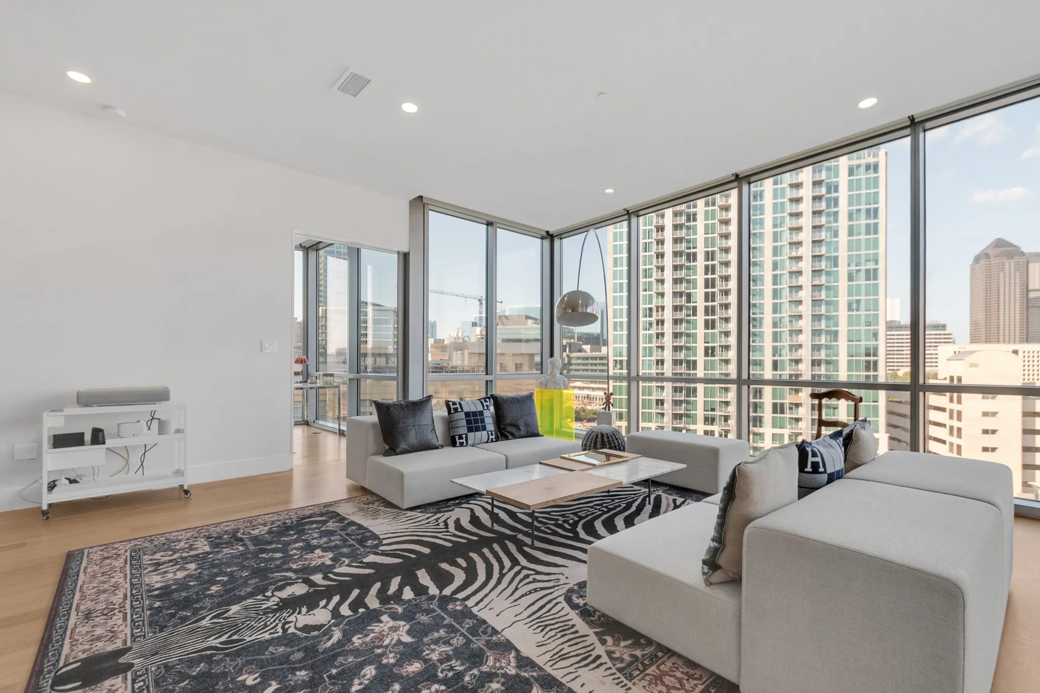 Expansive floor-to-ceiling windows, light wood-finish flooring, recessed lighting, and a glass-paneled door