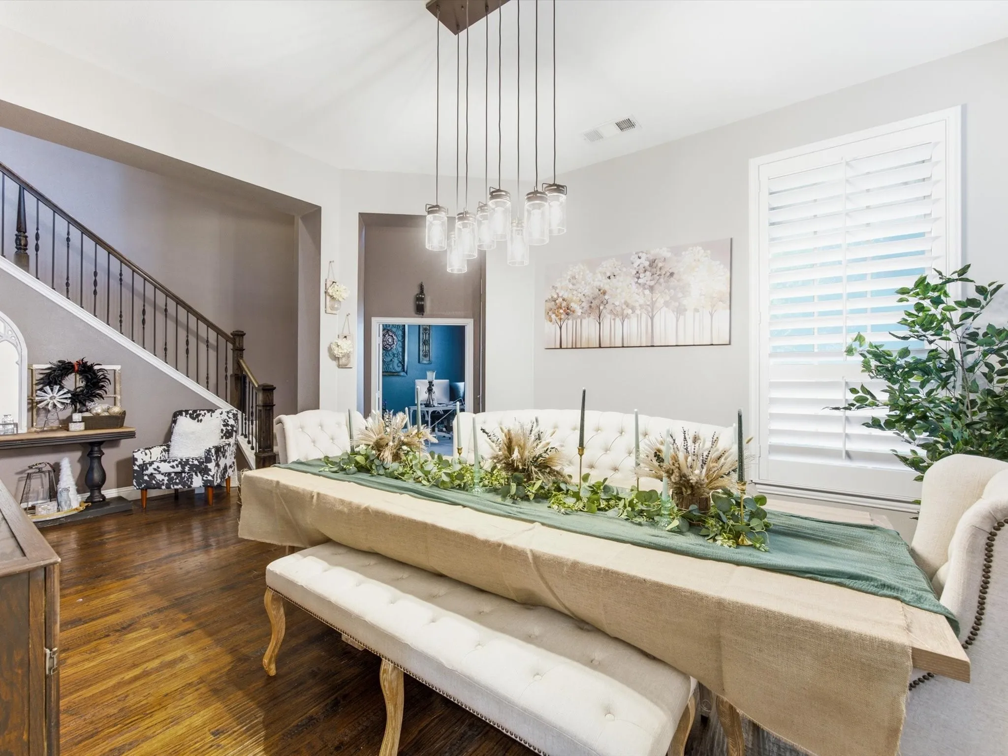 Dining space featuring a linear chandelier with mason jar lights, wood-finish flooring, and white plantation shutters