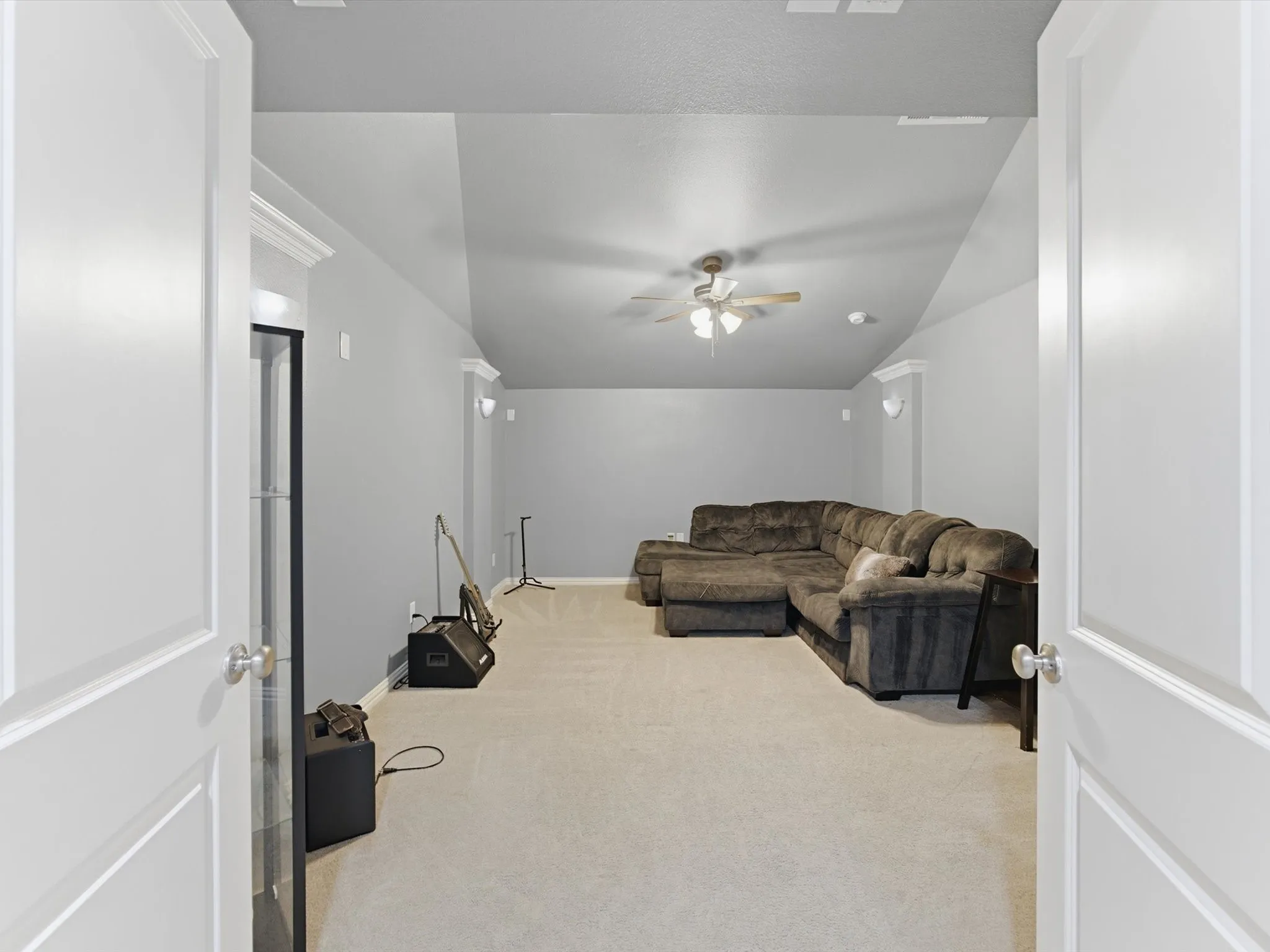 Carpeted Media Room featuring a vaulted ceiling with a fan, wall sconces, double doors, and crown molding accents