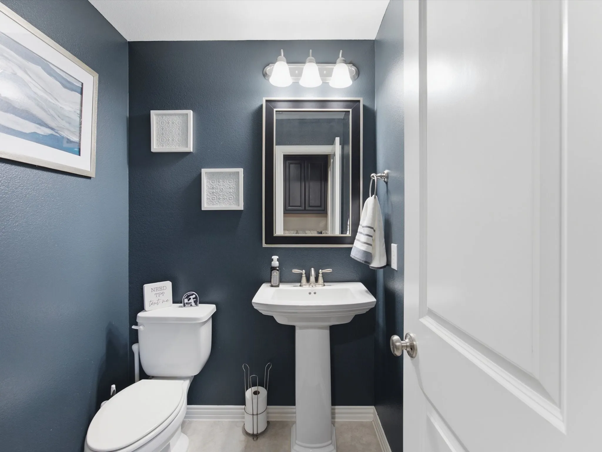 Powder room featuring a white pedestal sink with a chrome faucet, a white toilet, and dark blue walls