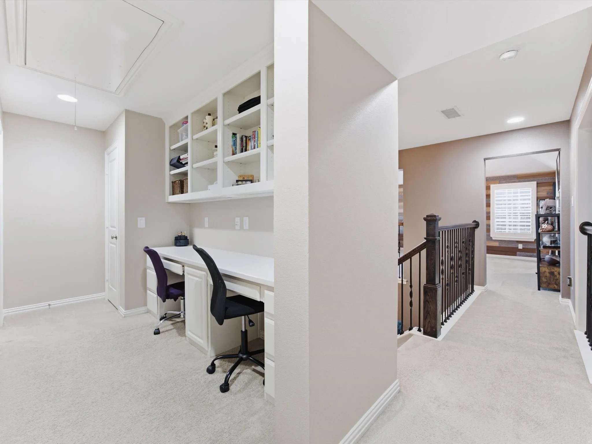 Carpeted hallway featuring a built-in desk with two workstations, integrated shelving, and recessed lighting