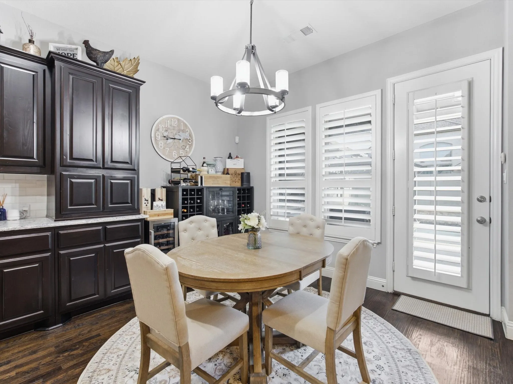 Dining area featuring dark wood-finish cabinetry, light stone-look countertops, and a subway tile backsplash