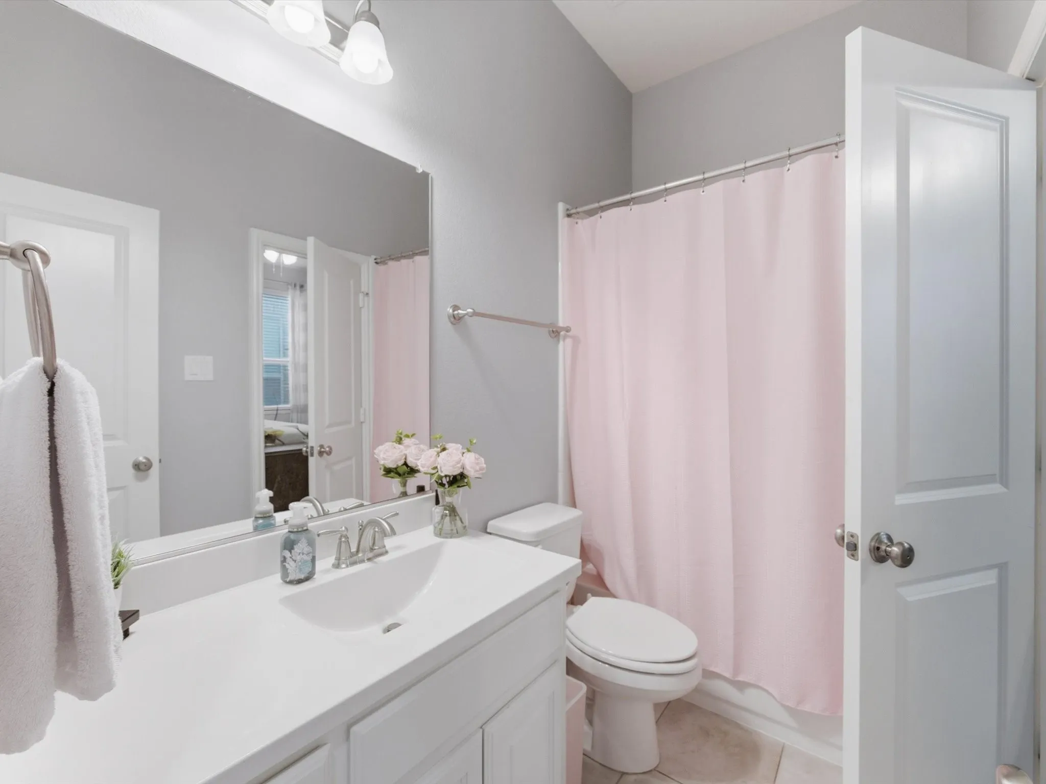 Bathroom featuring a spacious vanity with an integrated sink and brushed nickel faucet, large wall mirror, and overhead vanity lighting