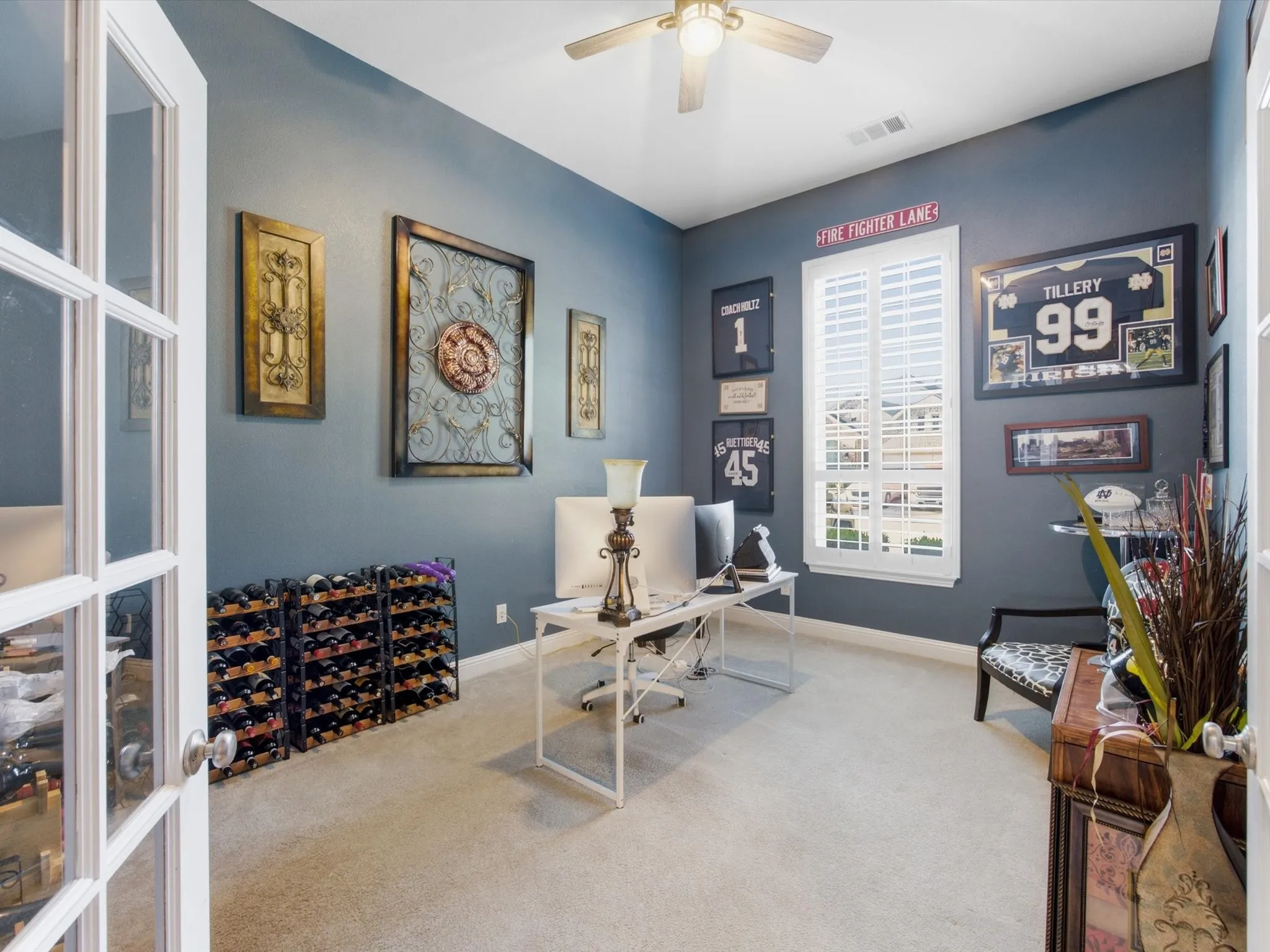 Versatile room featuring a large window with plantation shutters, ceiling fan with integrated lighting, and carpet flooring