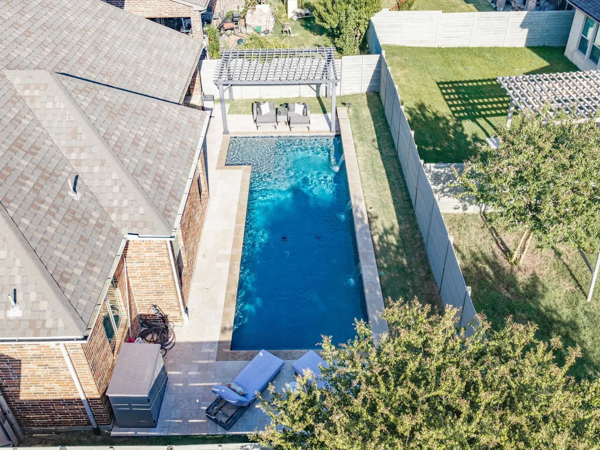 Aerial perspective showcasing a shingled roofline and a backyard oasis