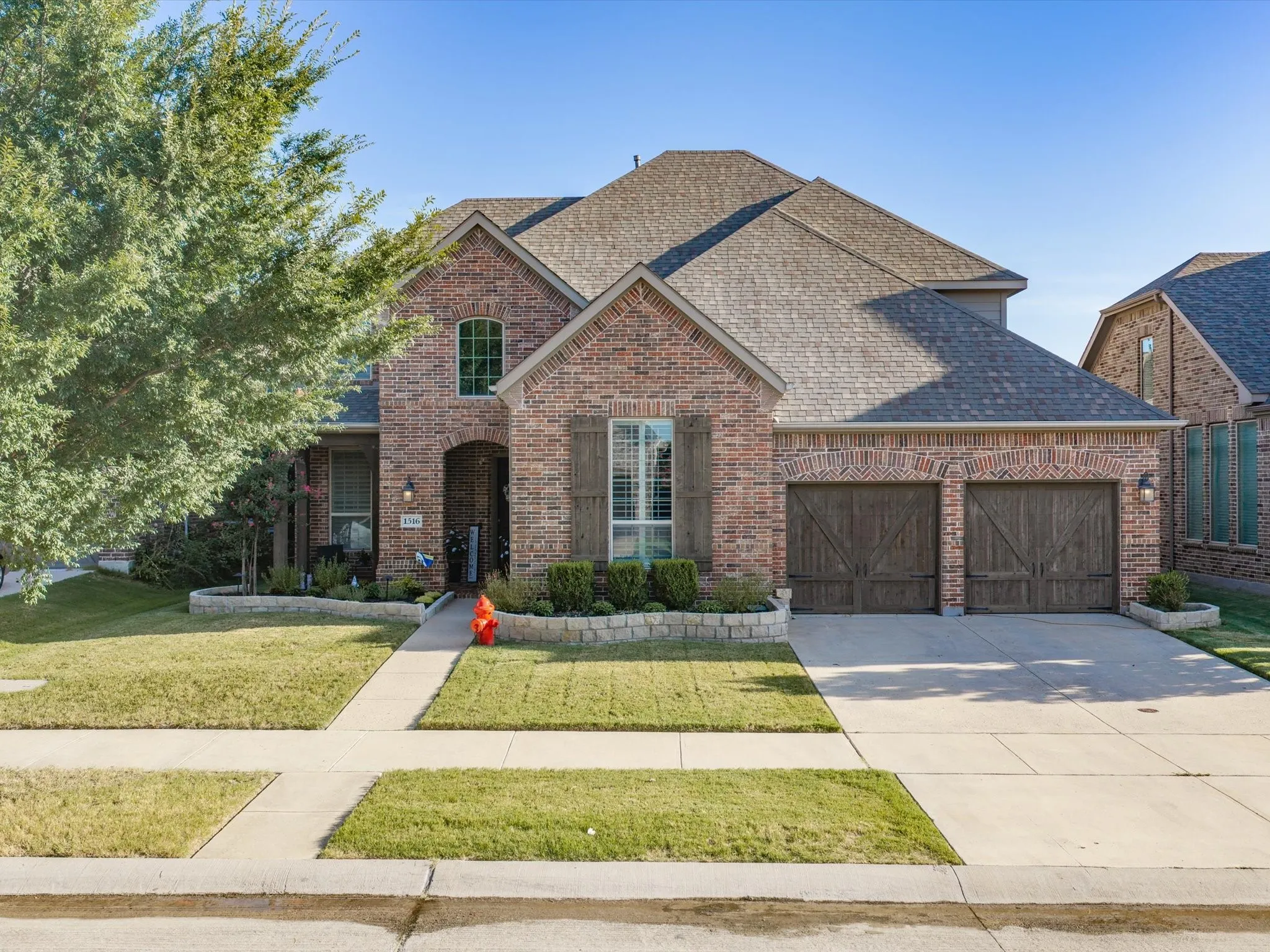 Brick exterior with an arched entryway and decorative wood-look garage doors