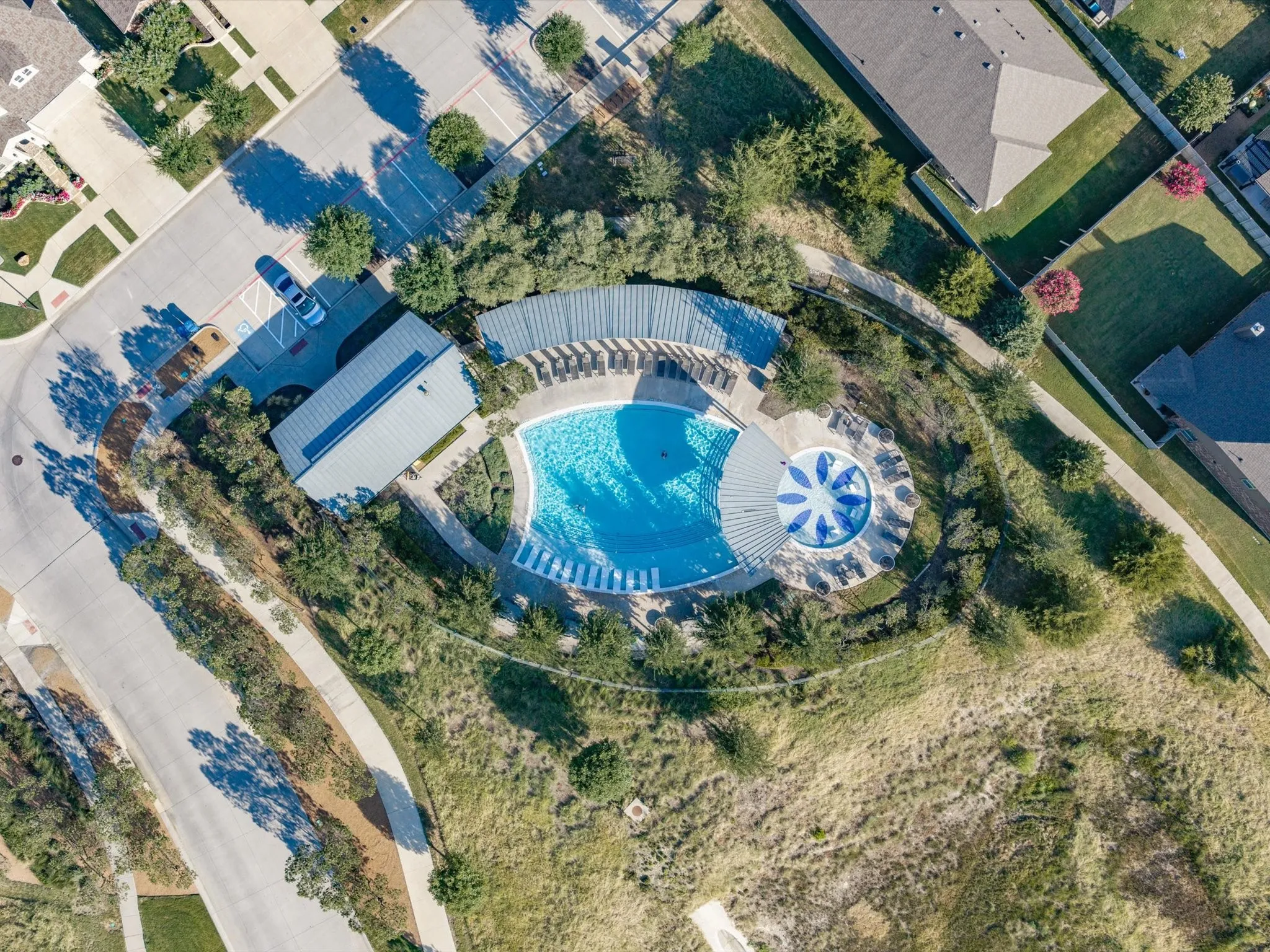 Resort-style community pool featuring a large swimming pool, circular splash pad with umbrella shade, and integrated lounge seating