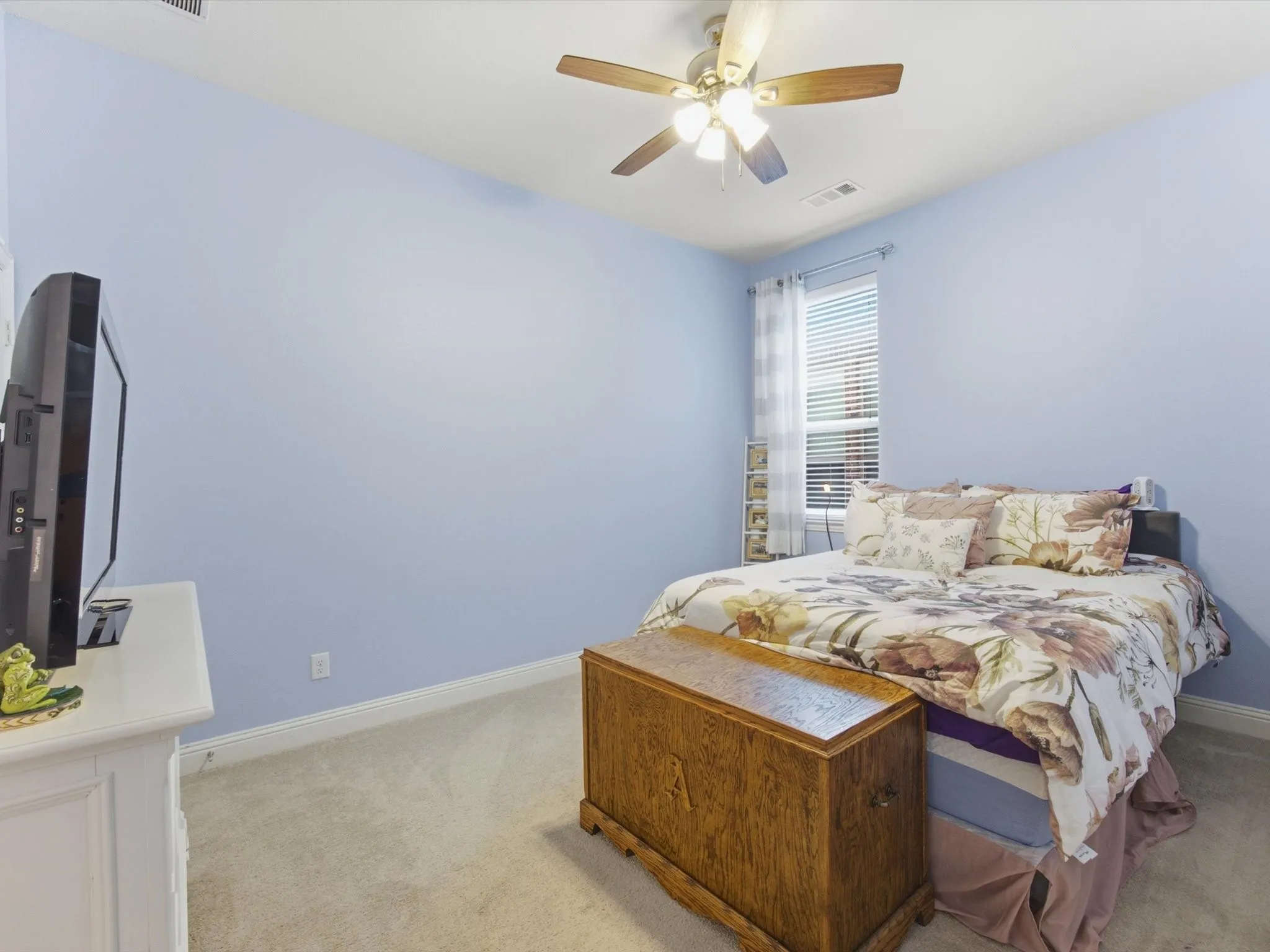 Carpeted room featuring a ceiling fan with integrated lighting, a window with blinds, and light blue walls