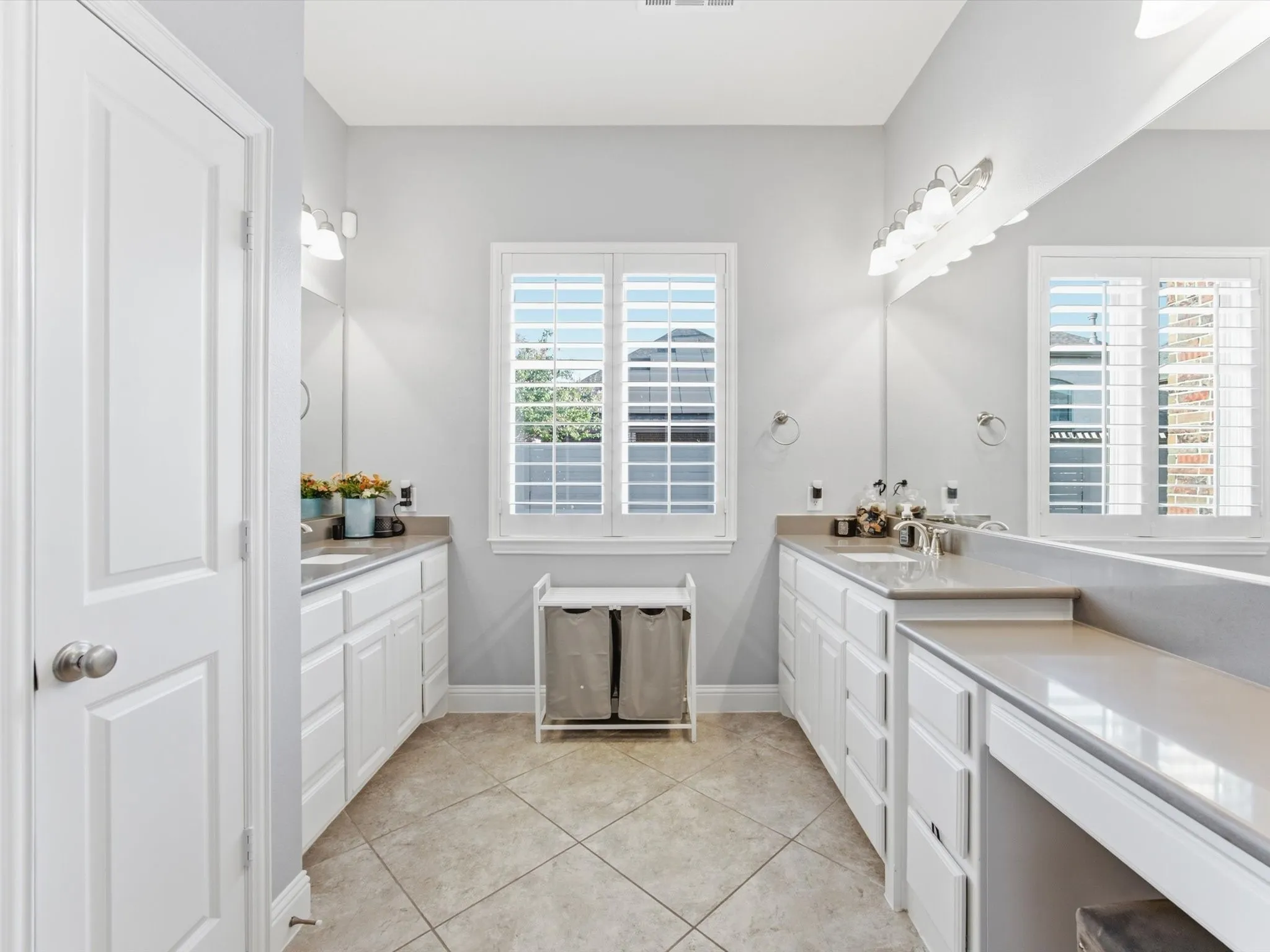 Well-appointed Primary Bathroom featuring dual vanities with integrated sinks, ample counter space, white cabinetry, and a dedicated vanity area