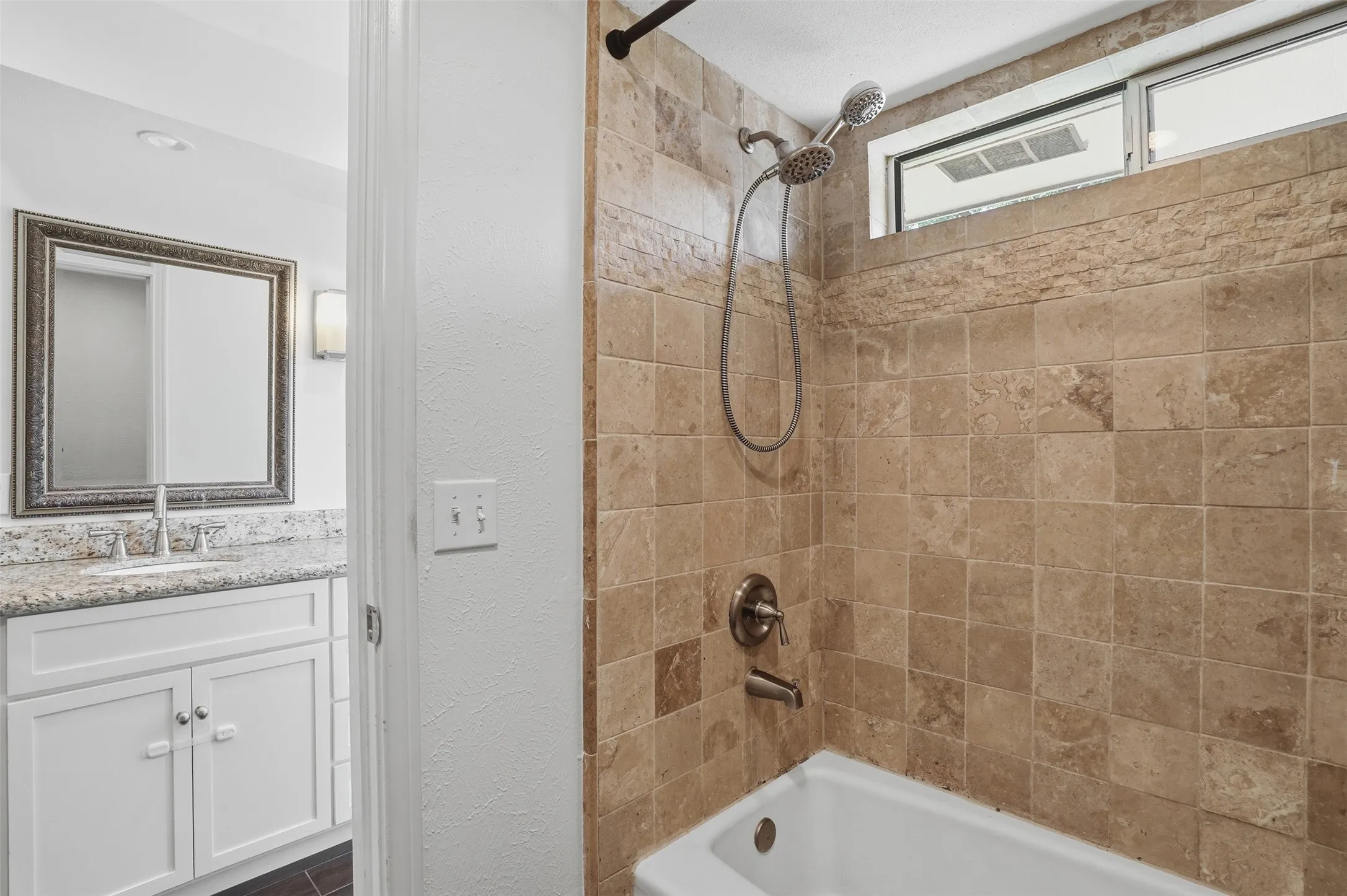 Tiled shower surround with a dual-head shower fixture and an upper transom window