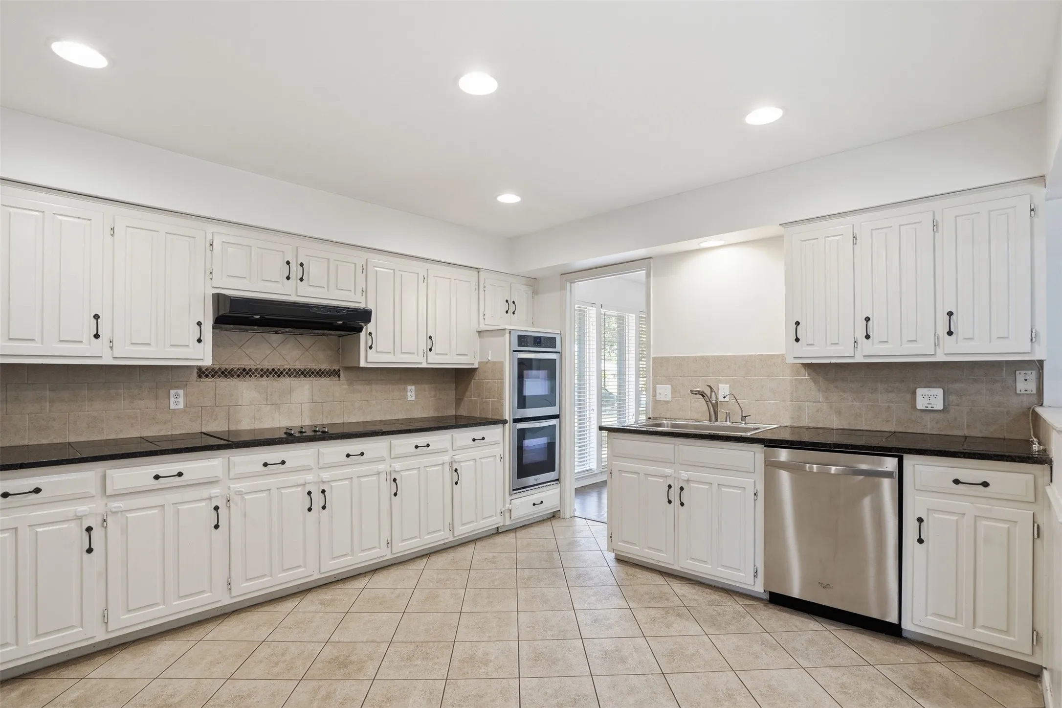 Kitchen featuring white cabinetry with dark hardware, dark countertops, and tile flooring
