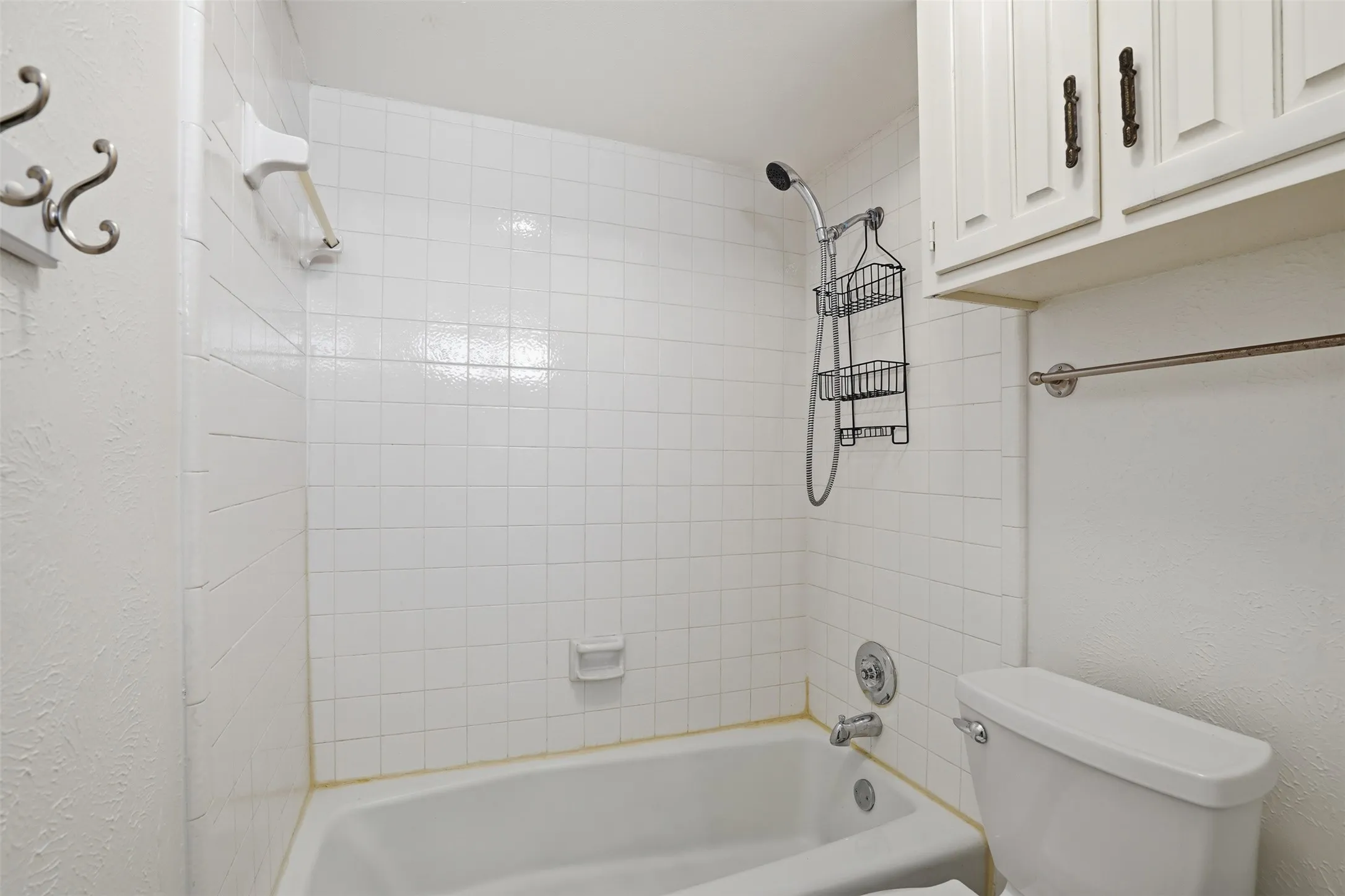 White tile shower surround with a fixed bathtub