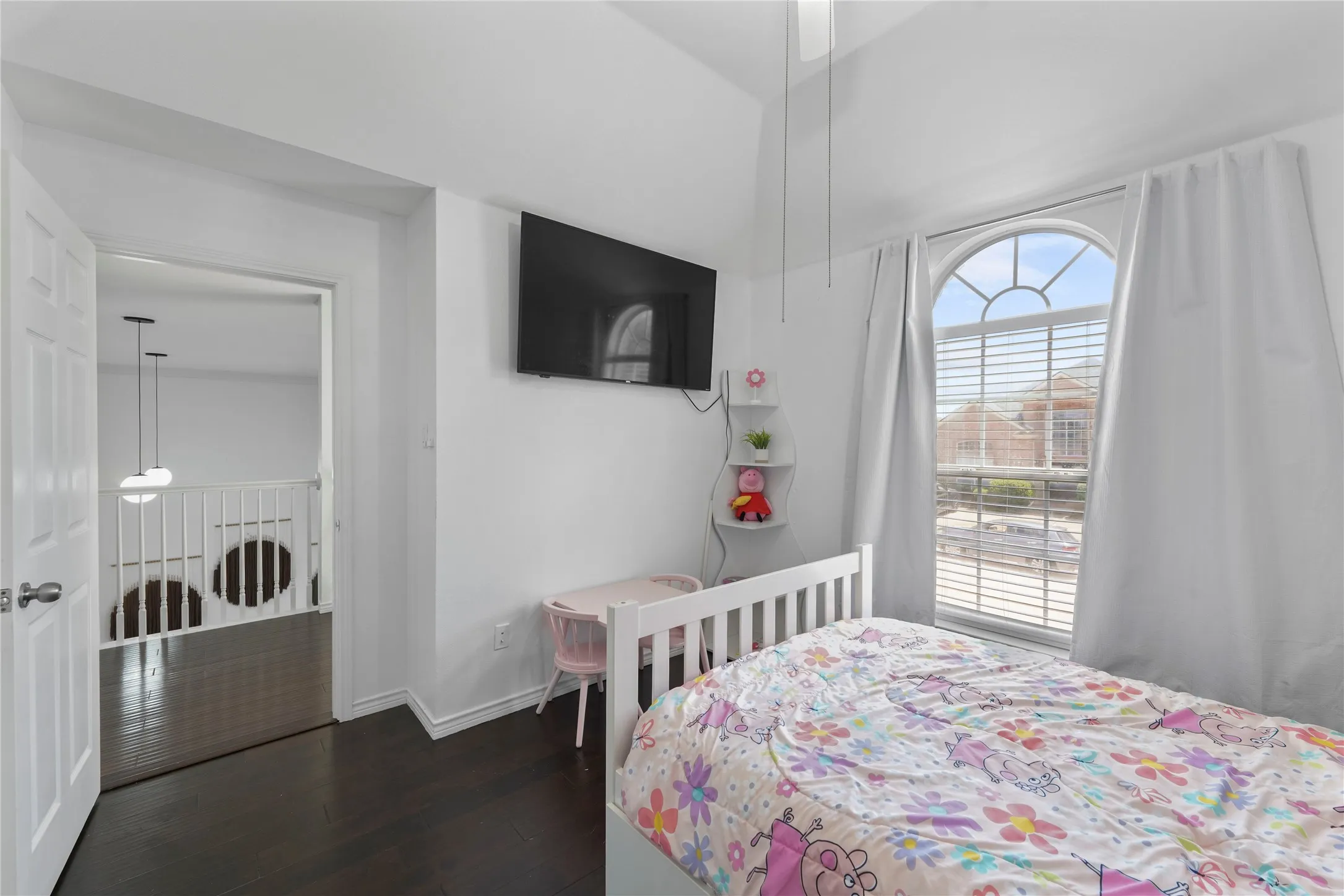Room featuring dark wood-finish flooring, an arched window with horizontal blinds, and a white ceiling fan