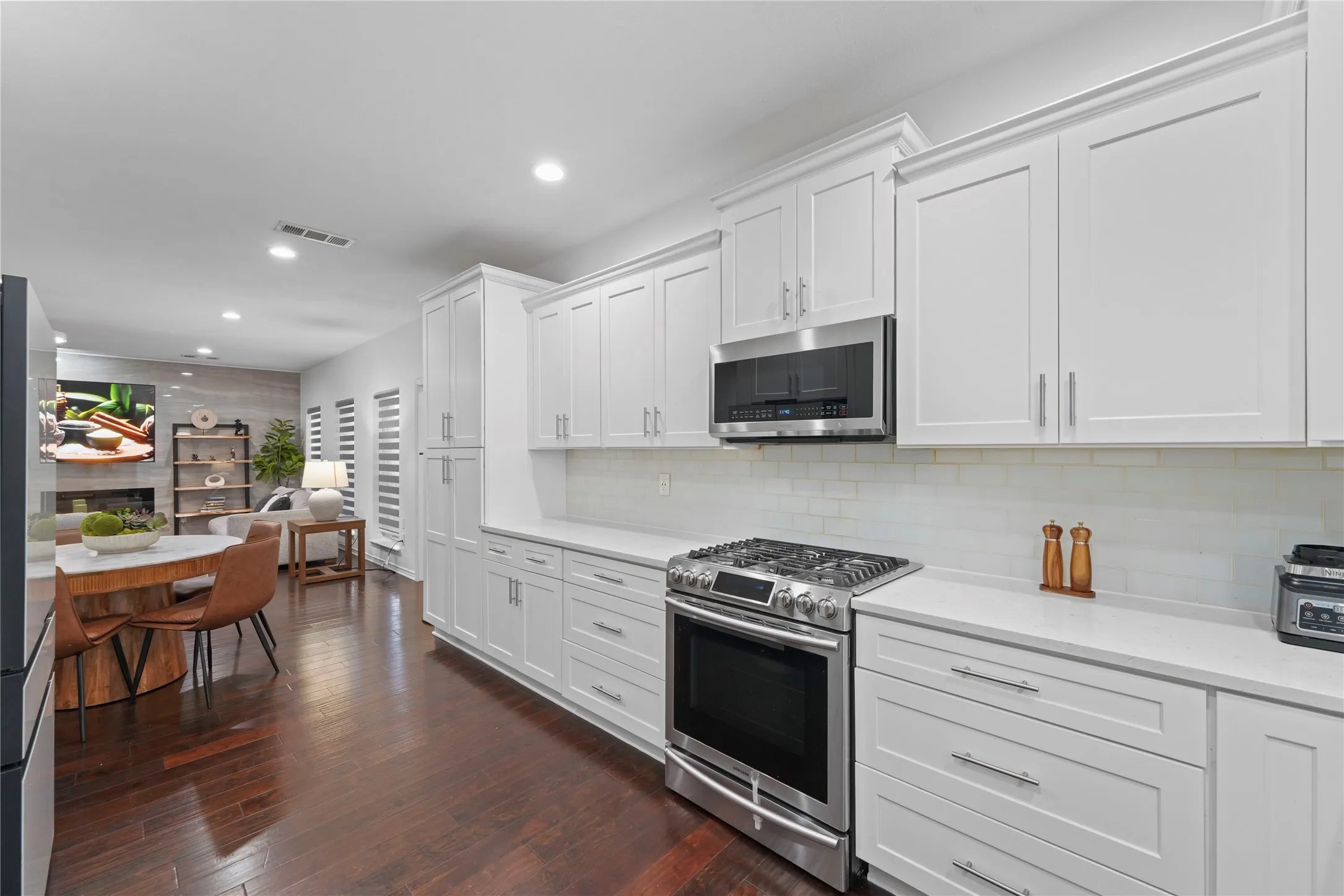Modern kitchen featuring white shaker-style cabinetry with chrome hardware, a stainless steel gas range, and a subway tile backsplash