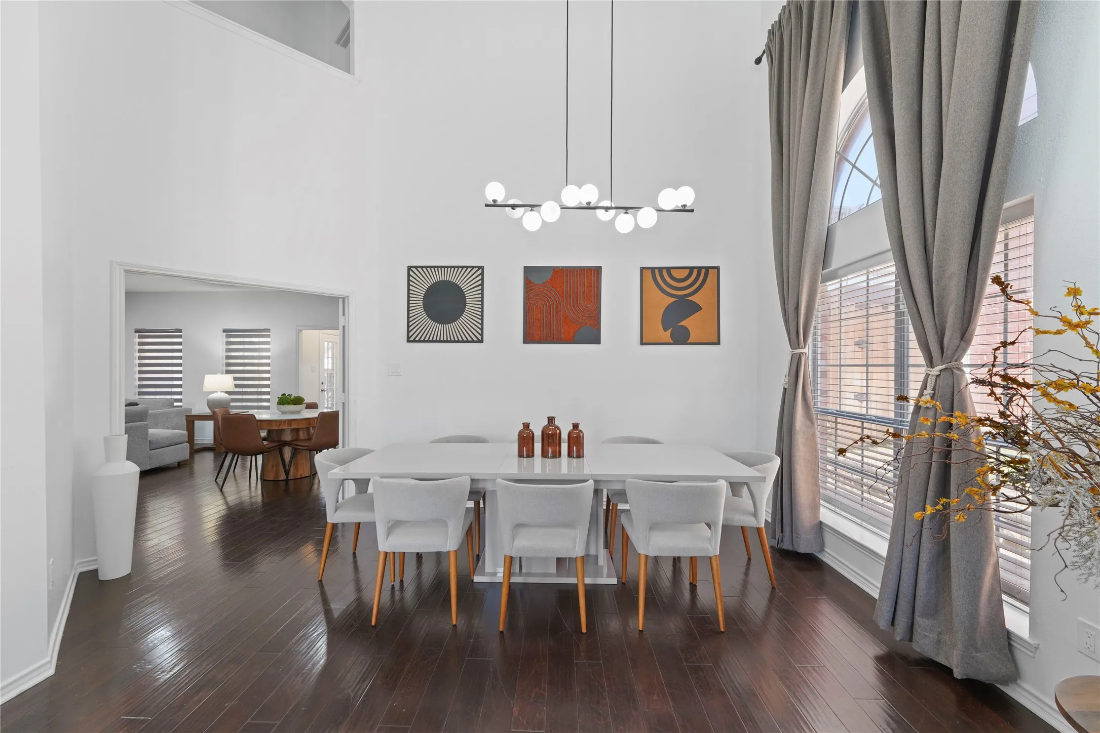 Dining area featuring dark wood-finish flooring, high ceilings, and a modern linear chandelier