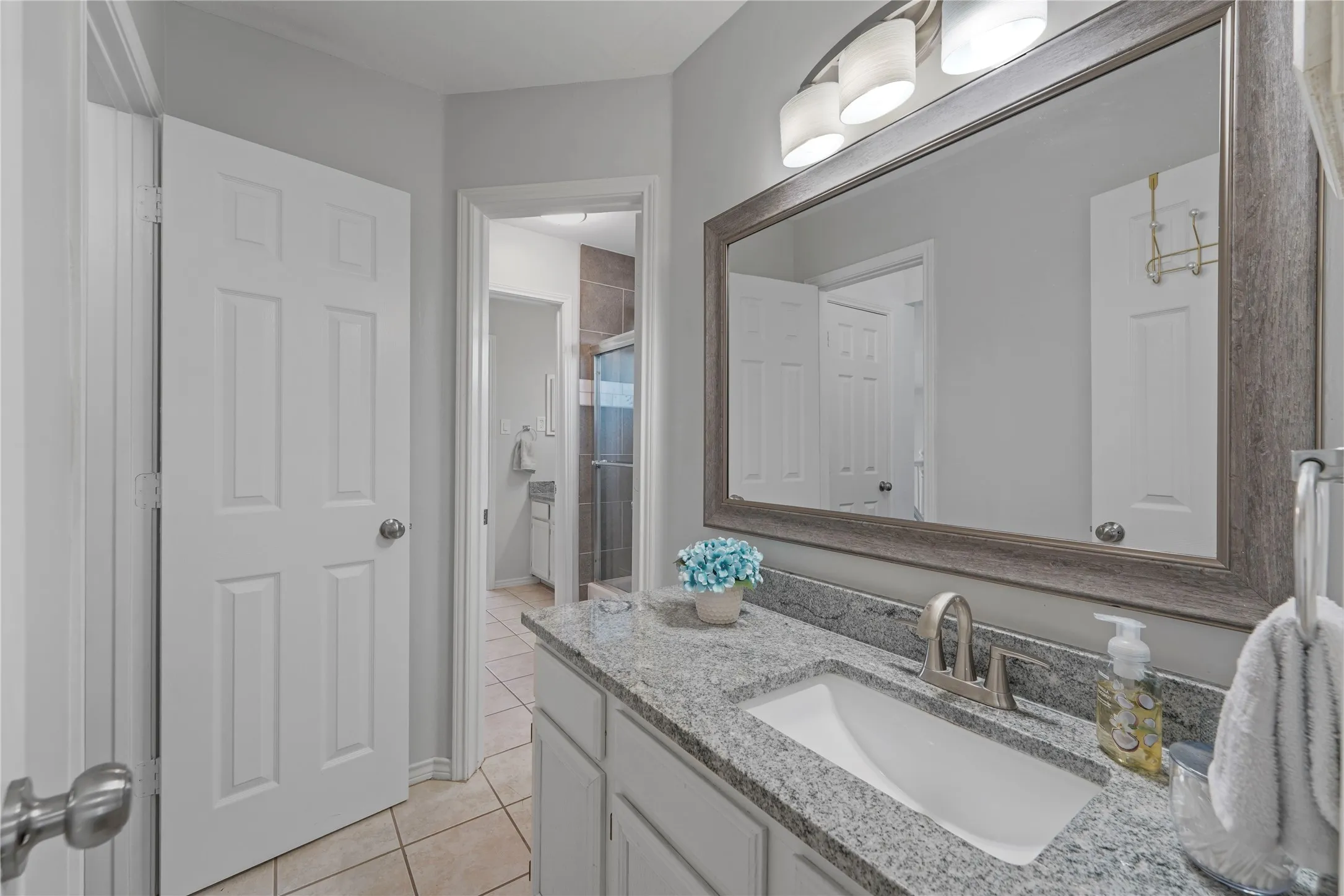 Bathroom vanity featuring a granite countertop with an undermount sink and brushed nickel faucet