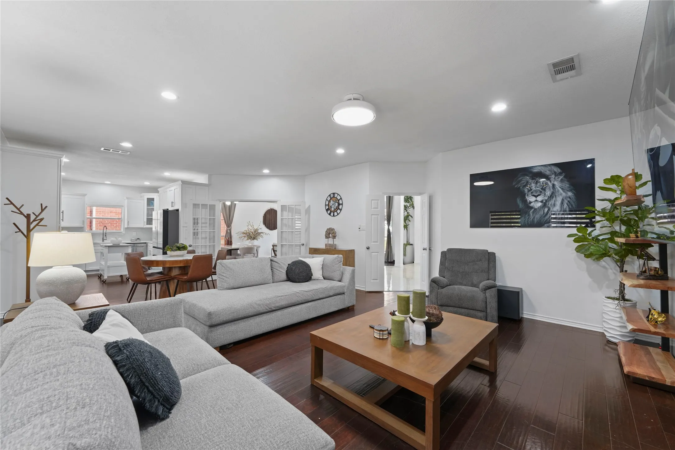 Open-concept living area featuring rich wood-finish flooring, recessed lighting, and crisp white walls