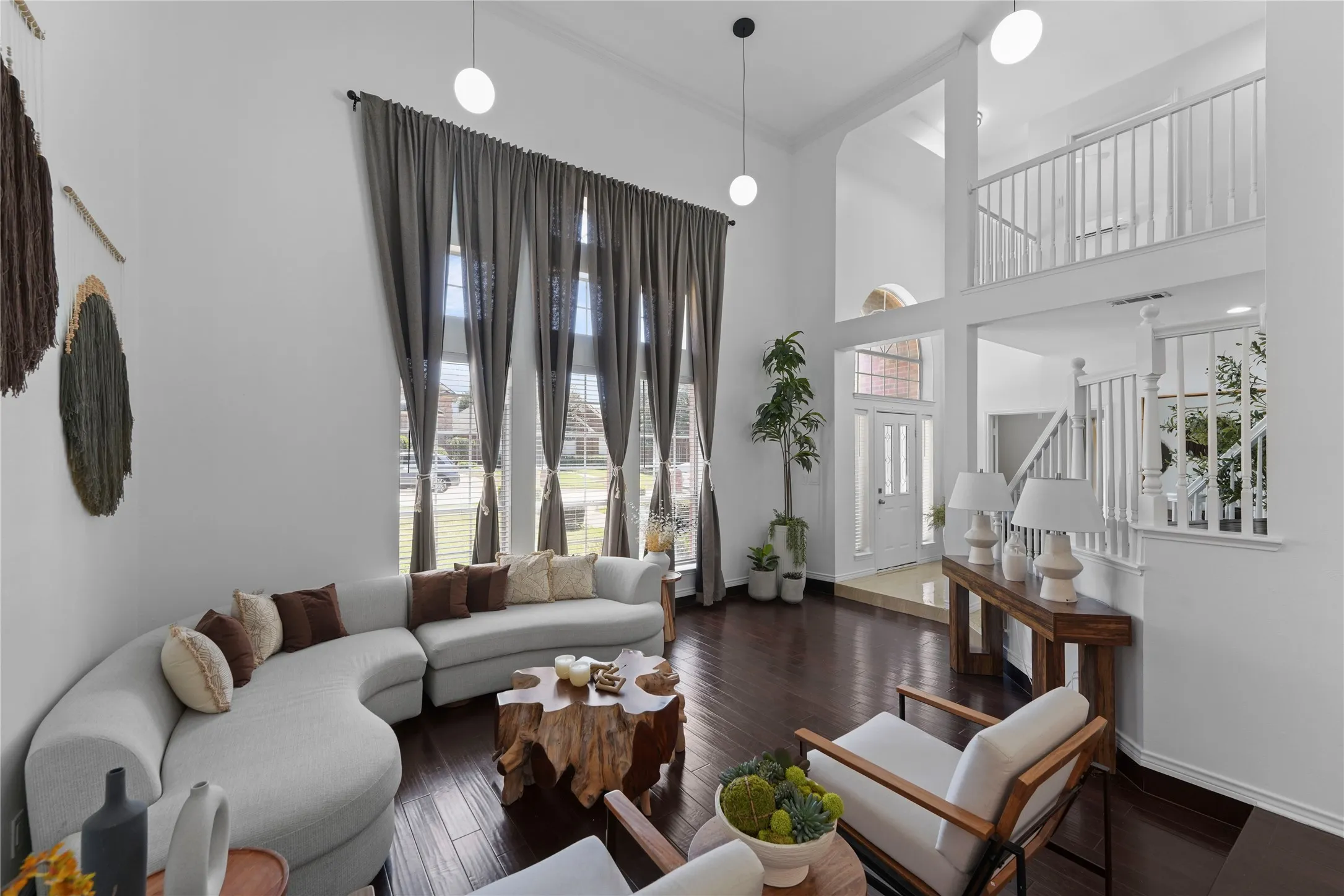 Grand living space featuring soaring ceilings, dark wood-finish flooring, and expansive windows