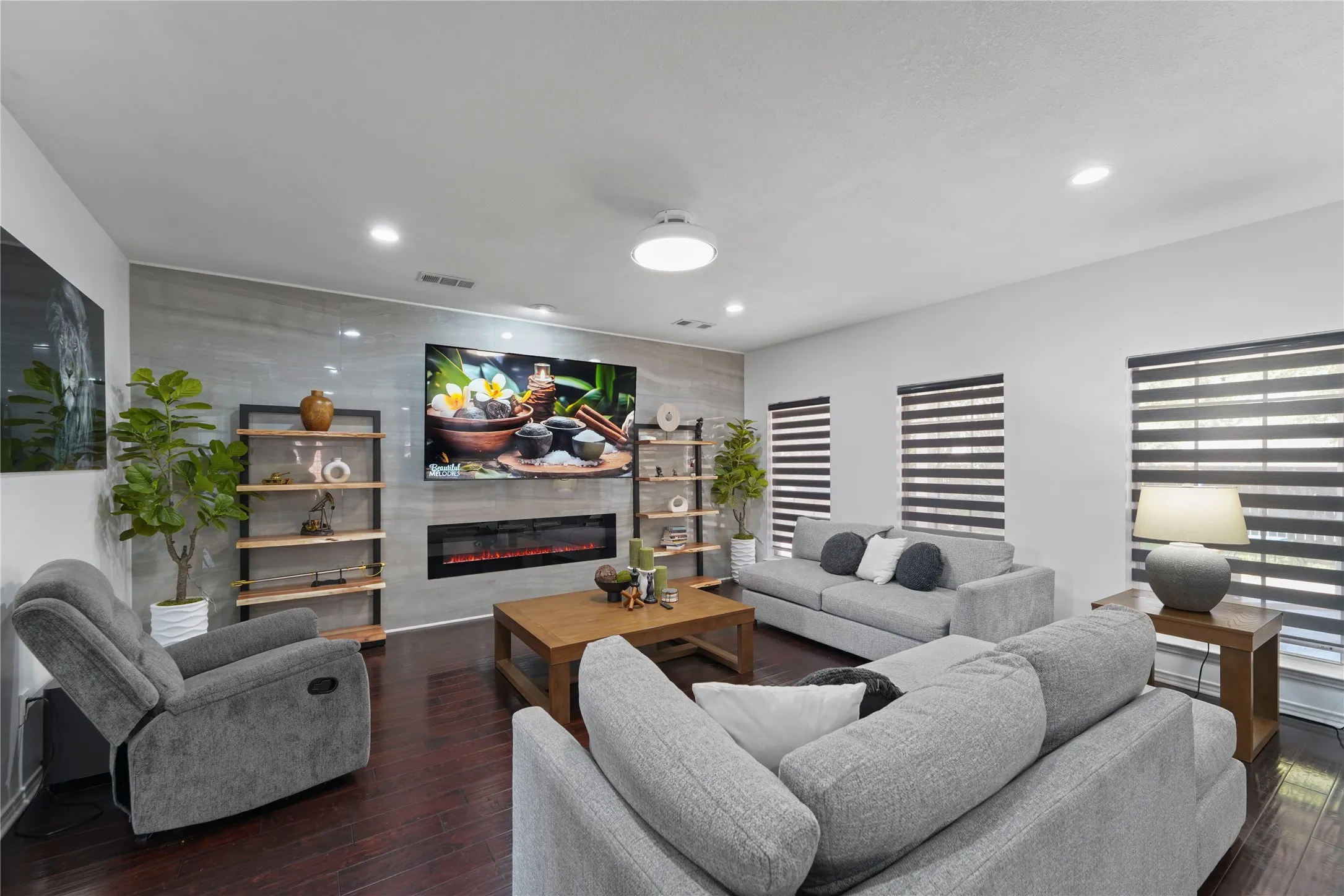 Living area featuring wood-finish flooring, recessed lighting, and a linear electric fireplace integrated into a large accent wall