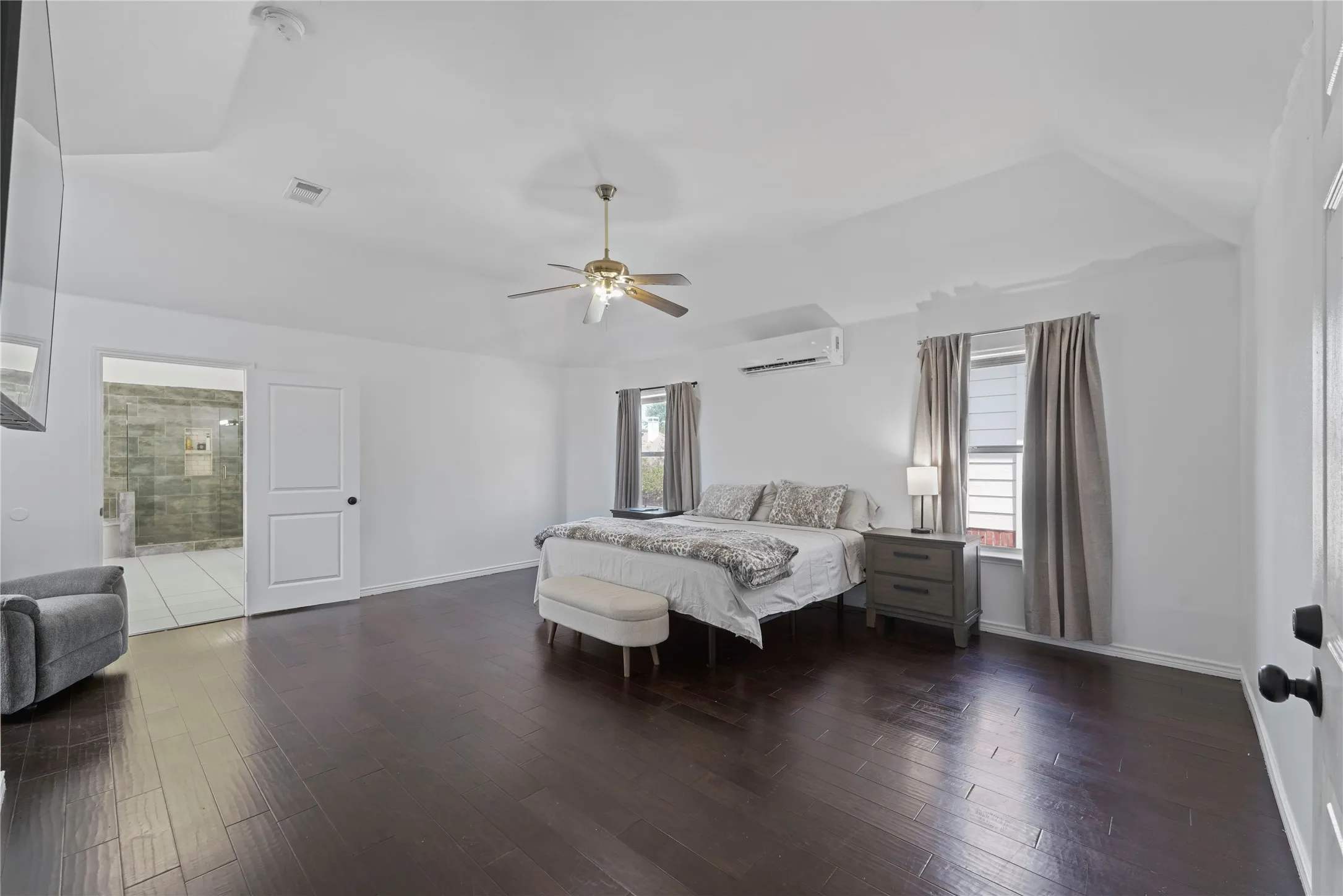 Expansive interior space featuring dark wood-finish flooring, white walls, and a vaulted ceiling