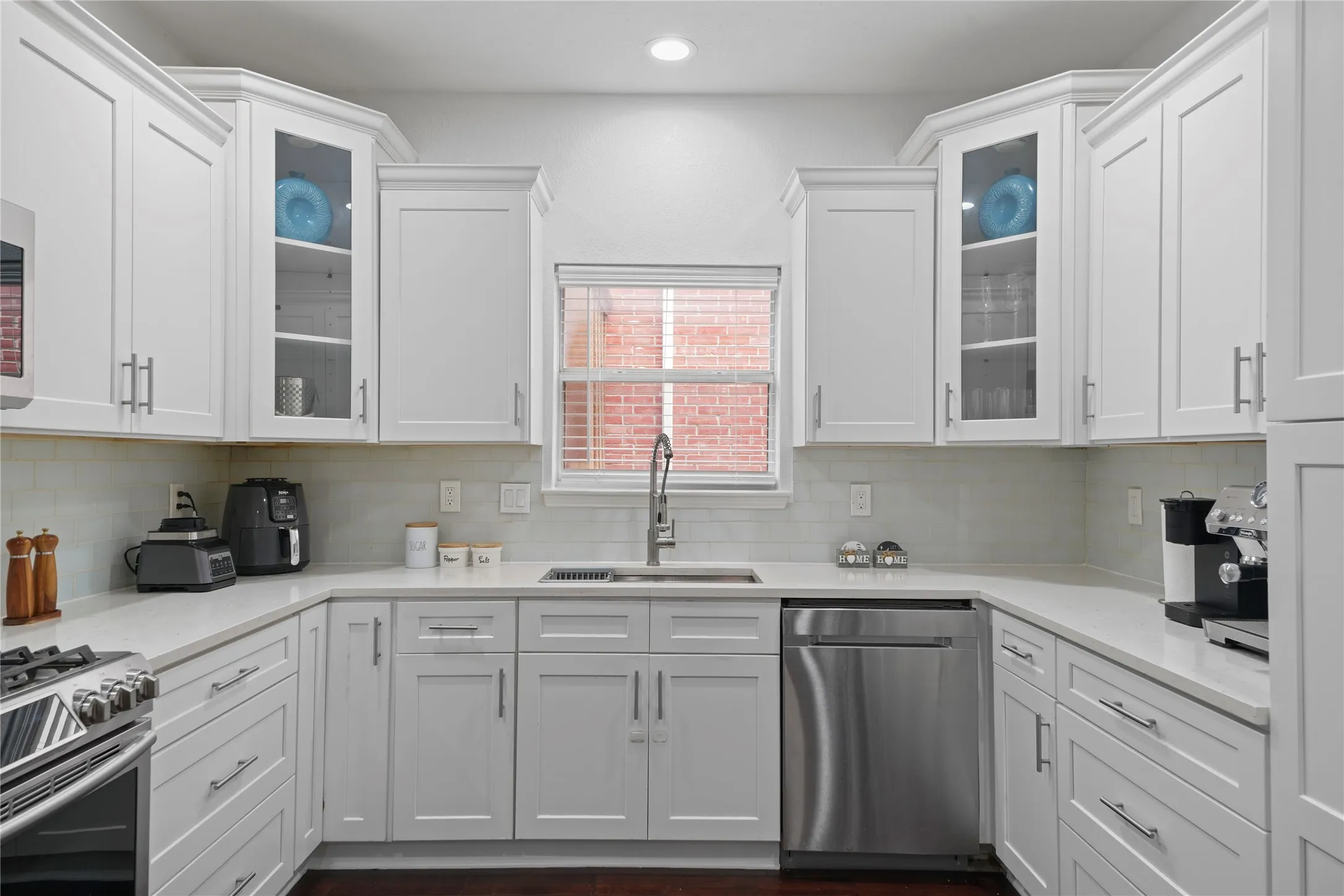 U-shaped kitchen featuring white shaker-style cabinetry, light countertops, and a subway tile backsplash