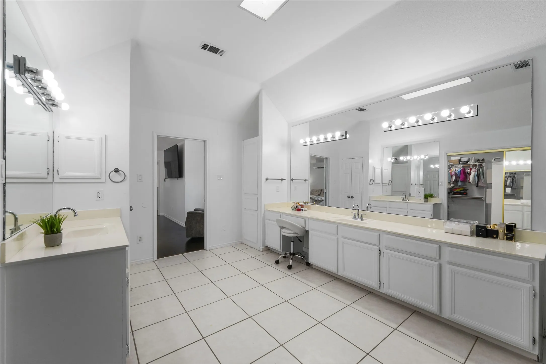 Spacious bathroom featuring white tiled flooring and a vaulted ceiling