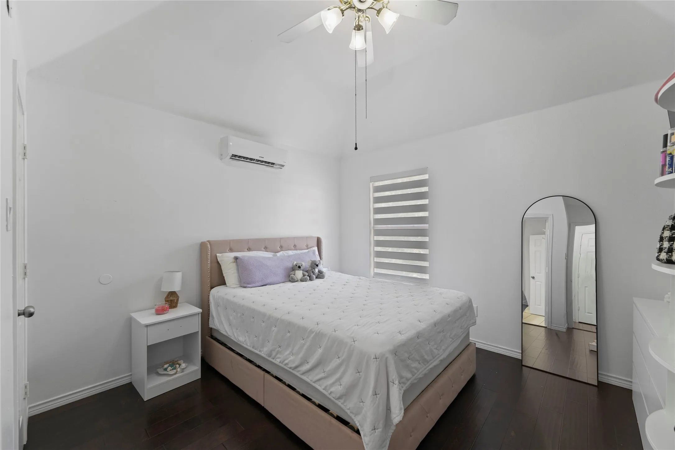 Bedroom featuring dark wood-finish flooring, white walls, and a ceiling fan with integrated lighting