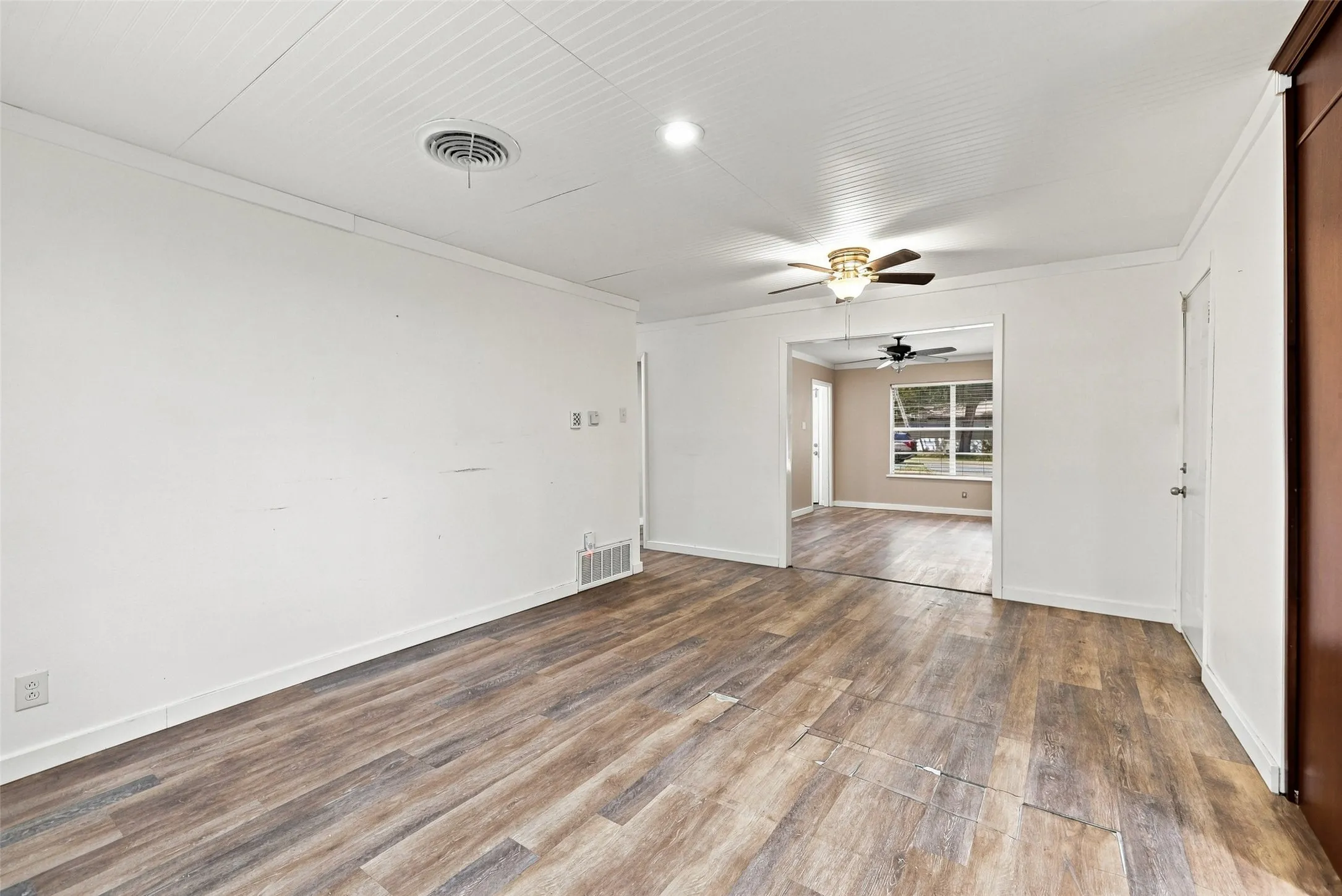 Wood-finish flooring, white walls, and a ceiling fan with integrated lighting
