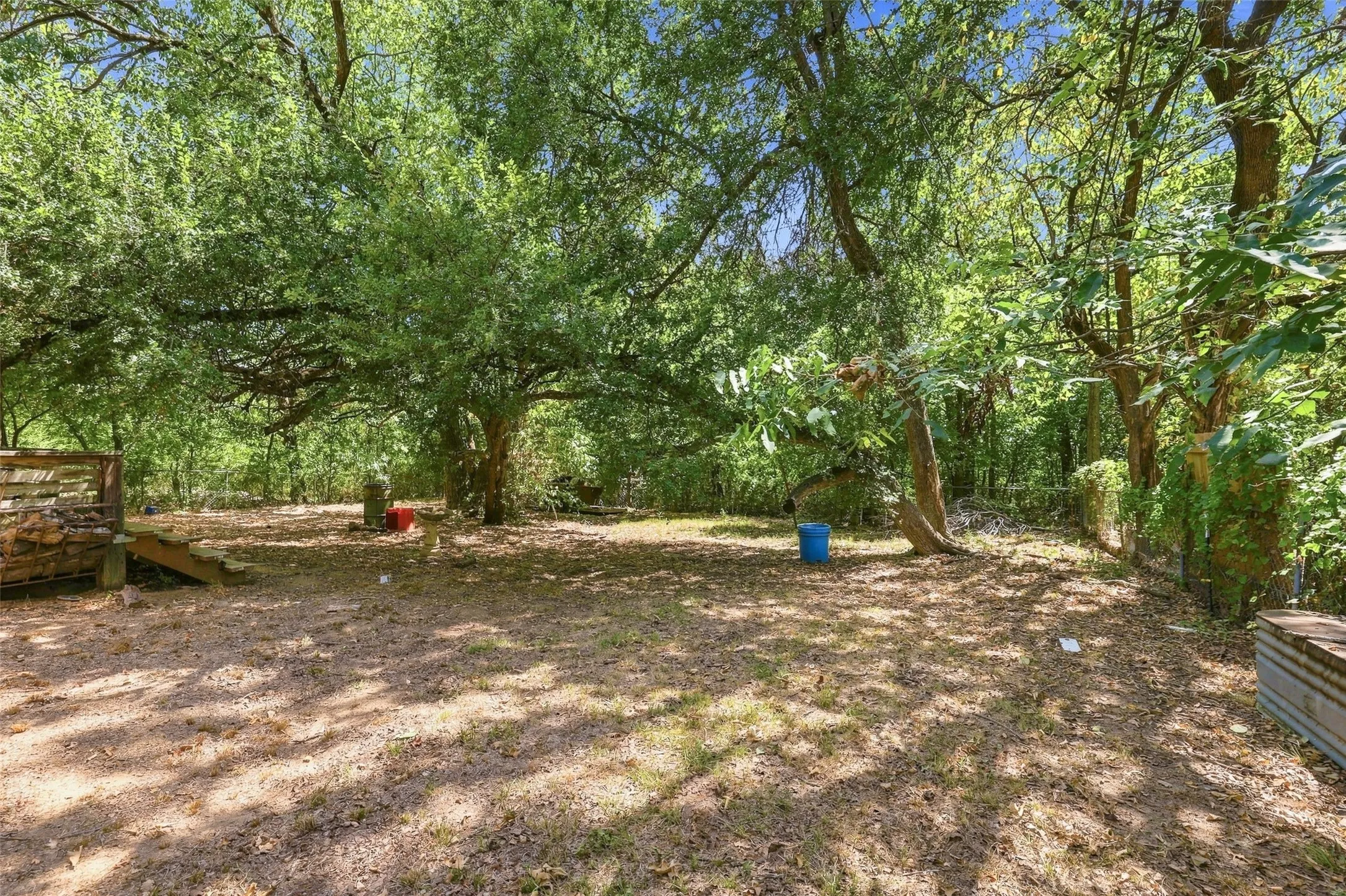 Expansive outdoor space featuring mature trees, a wooden deck structure, and natural ground cover