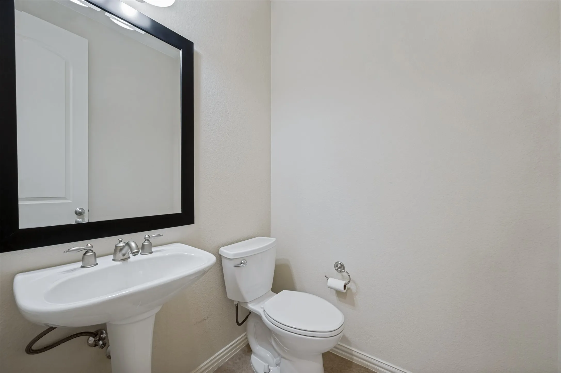 Conveniently located just off the main living spaces, this stylish powder bath features a classic pedestal sink, elegant framed mirror, and timeless finishes, making it ideal for guests.