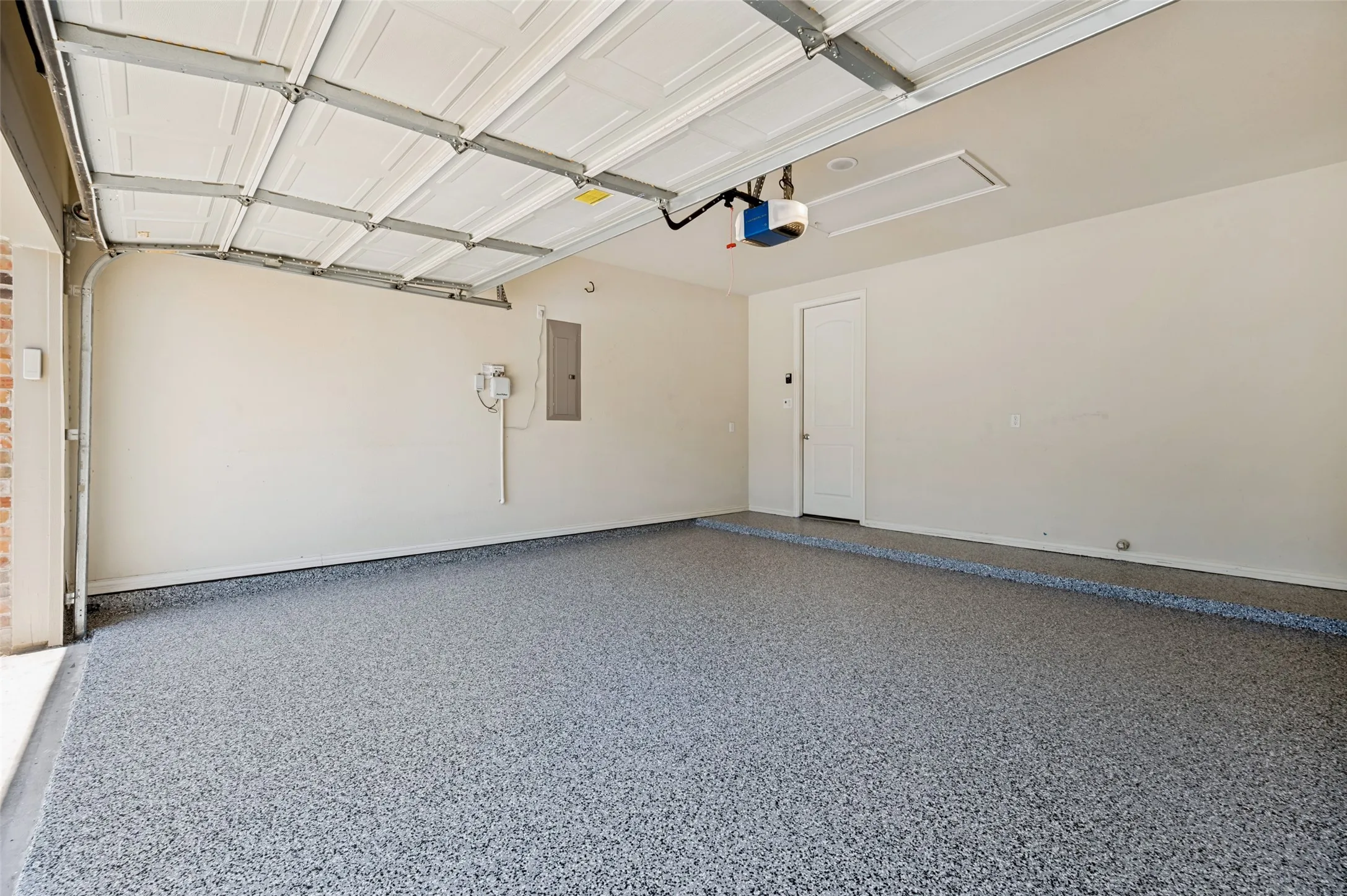 Freshly epoxied garage with a durable, low-maintenance floor coating, attic access, and plenty of space for parking, storage, or a workshop.