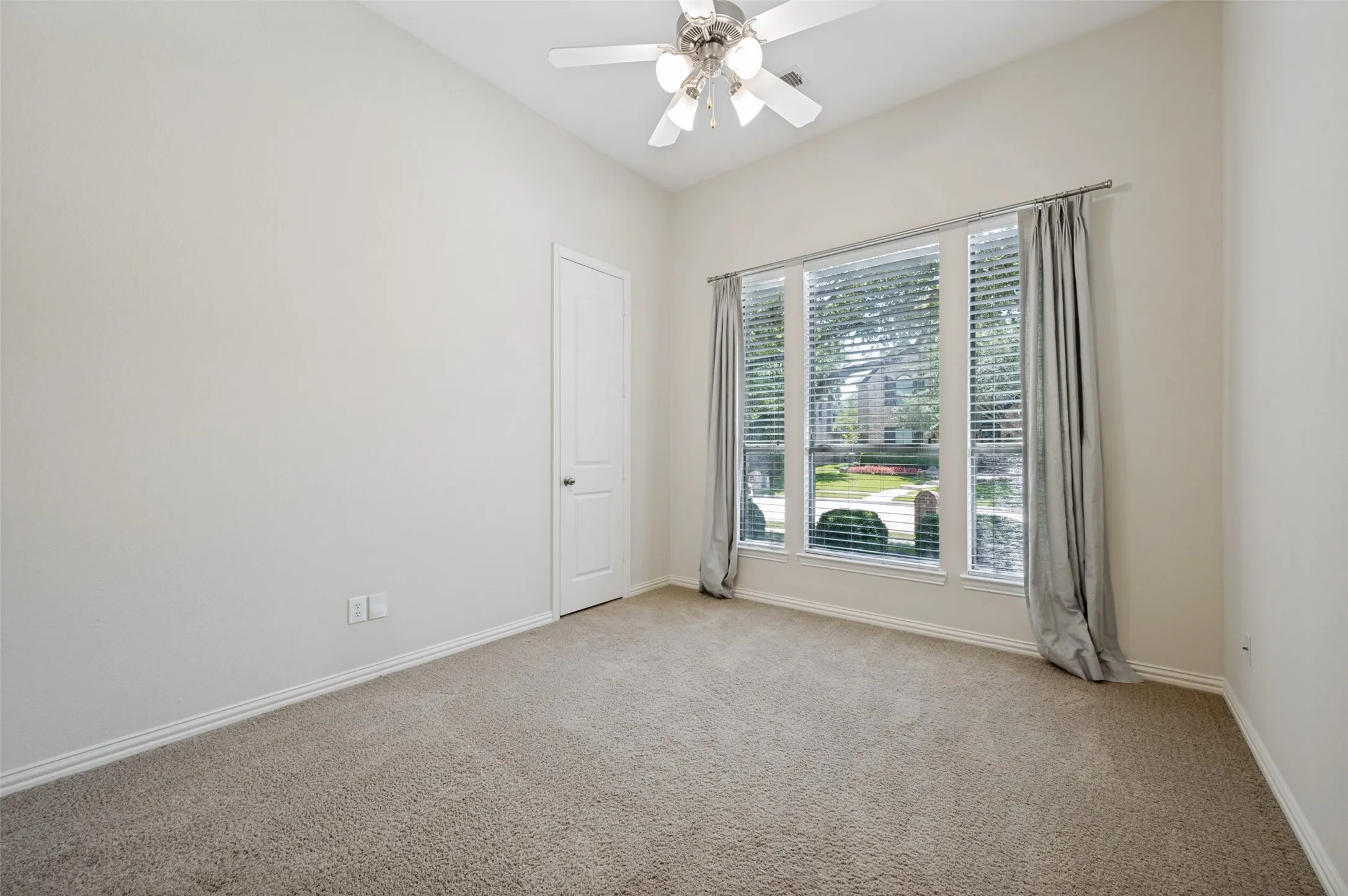 Spacious secondary bedroom featuring large front-facing windows that fill the room with natural light, soaring ceilings, and a generously sized closet. A versatile space perfect for family, guests, or a home office with comfortable accommodations and timeless finishes.