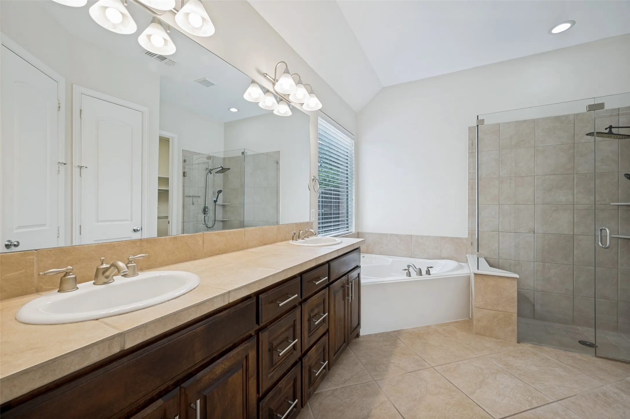 Escape to the spacious primary bath, thoughtfully designed with comfort and luxury in mind. An oversized dual-sink vanity with abundant cabinetry, generous counter space, and an expansive wall-to-wall mirror provides plenty of room for busy mornings.