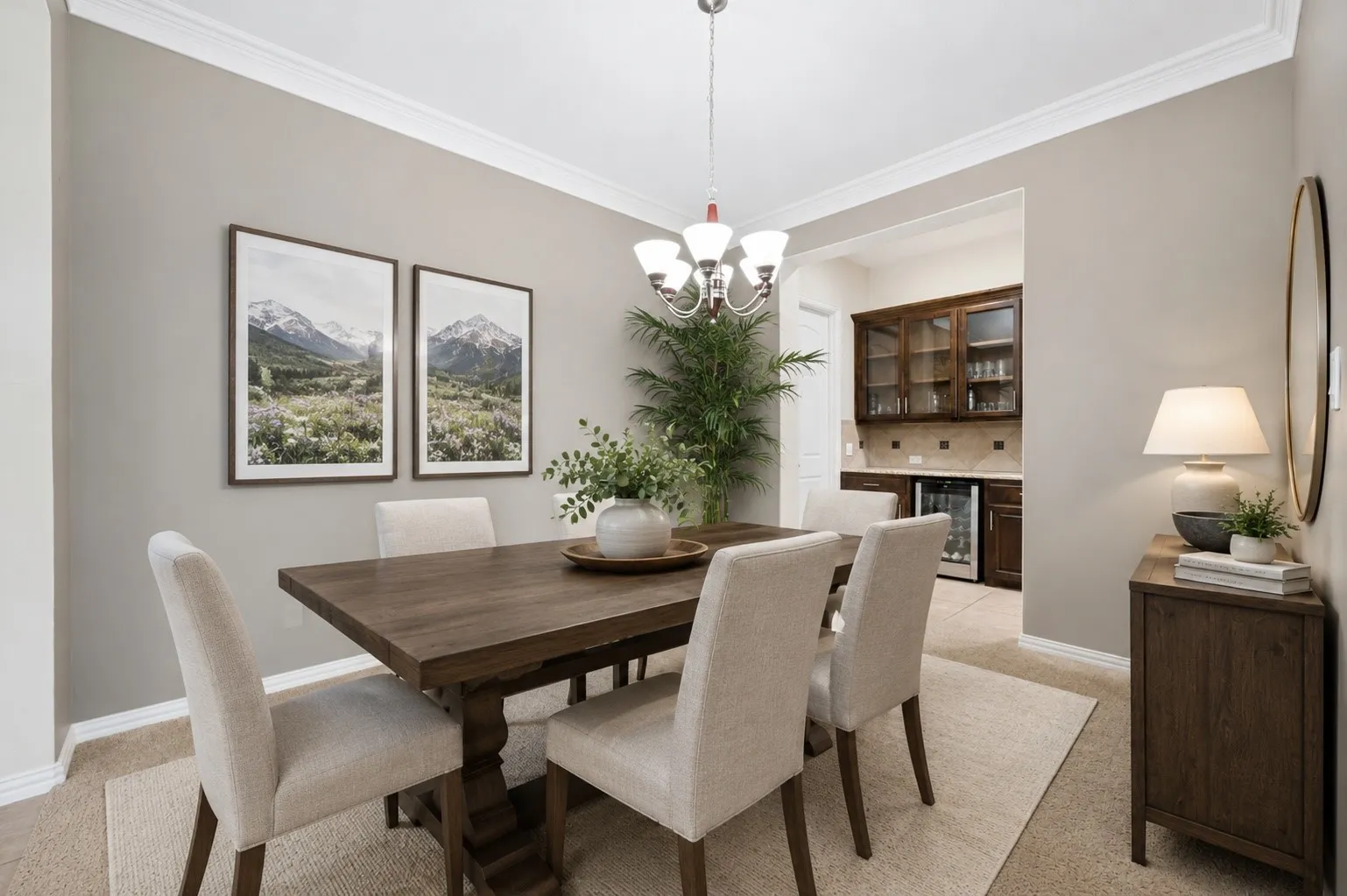 Elegant formal dining room featuring crown molding, designer lighting, and neutral finishes. Conveniently connected to the serving area with built-in cabinetry and a beverage refrigerator, making entertaining both stylish and effortless. This image has been virtually staged using AI.