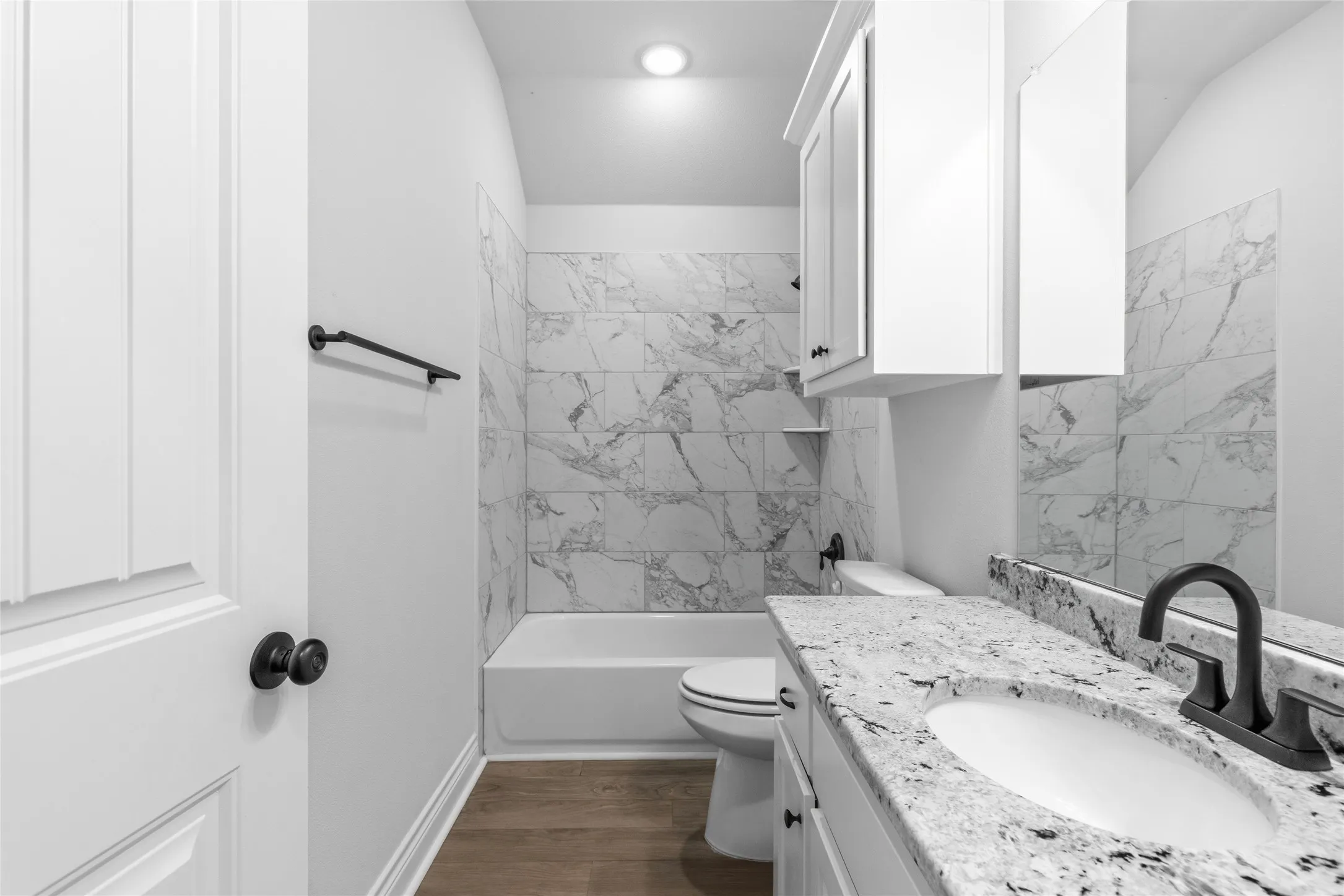 Bathroom featuring a single vanity with stone-finish countertop, under-mount sink, and matte black faucet