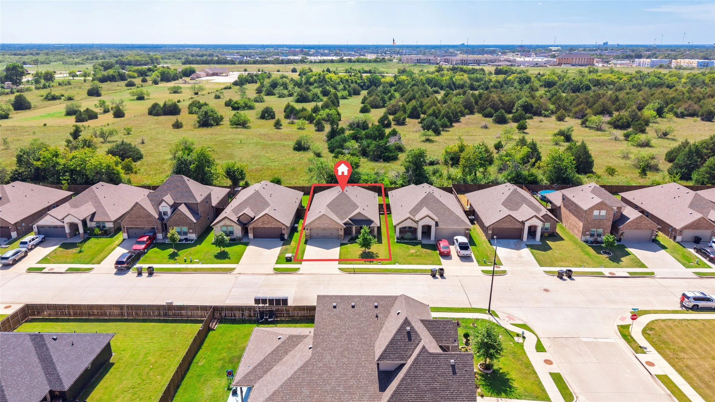 Aerial perspective showcasing a single-story residence with a tan brick exterior and a brown shingle roof