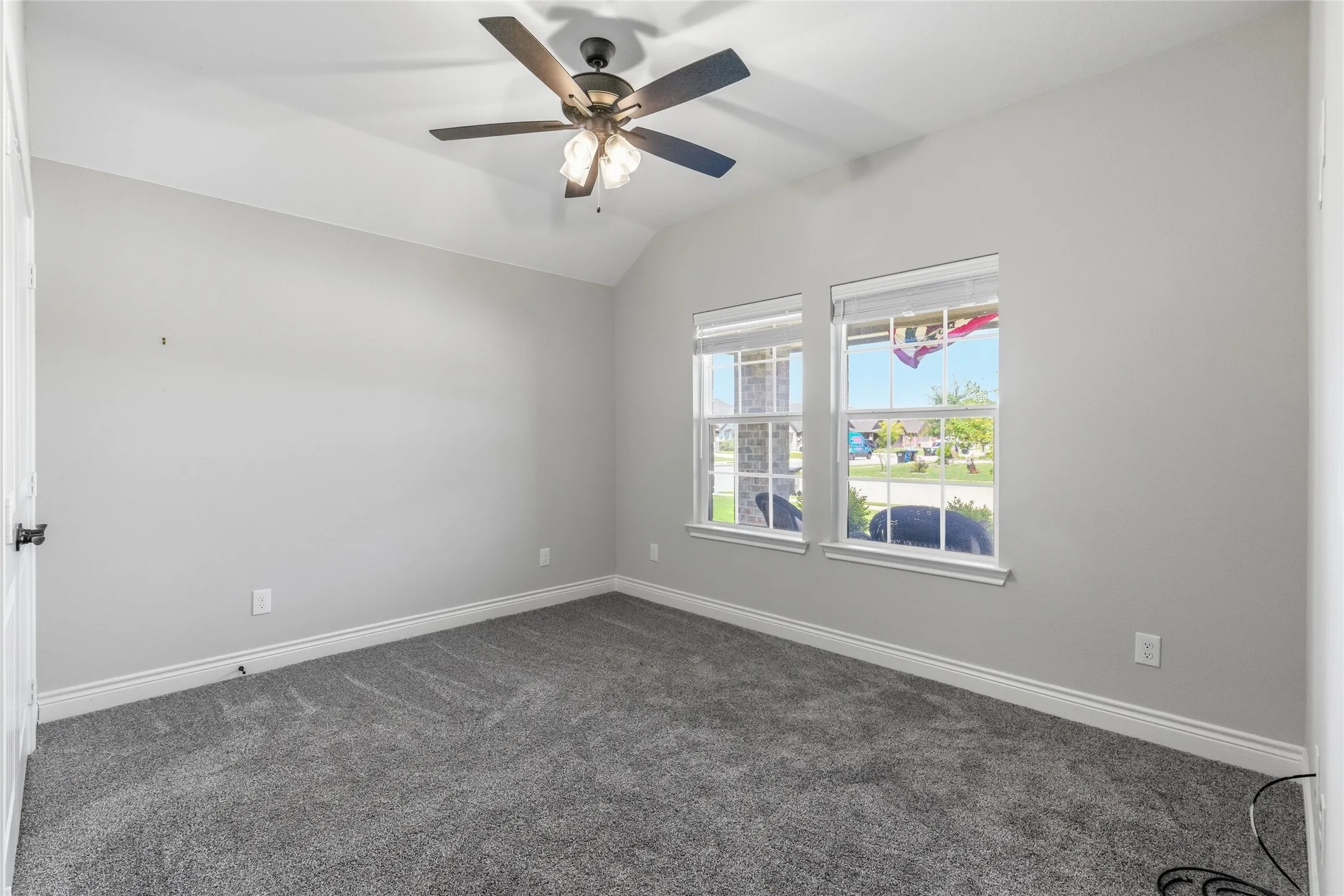 Spacious room featuring vaulted ceilings, gray carpeting, and white baseboards