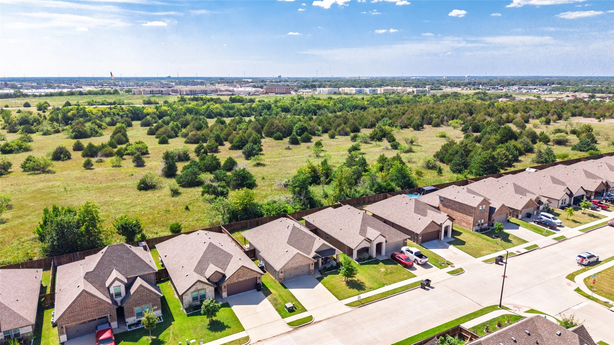 Aerial perspective of a residential street featuring single-family homes with brick exteriors and attached garages