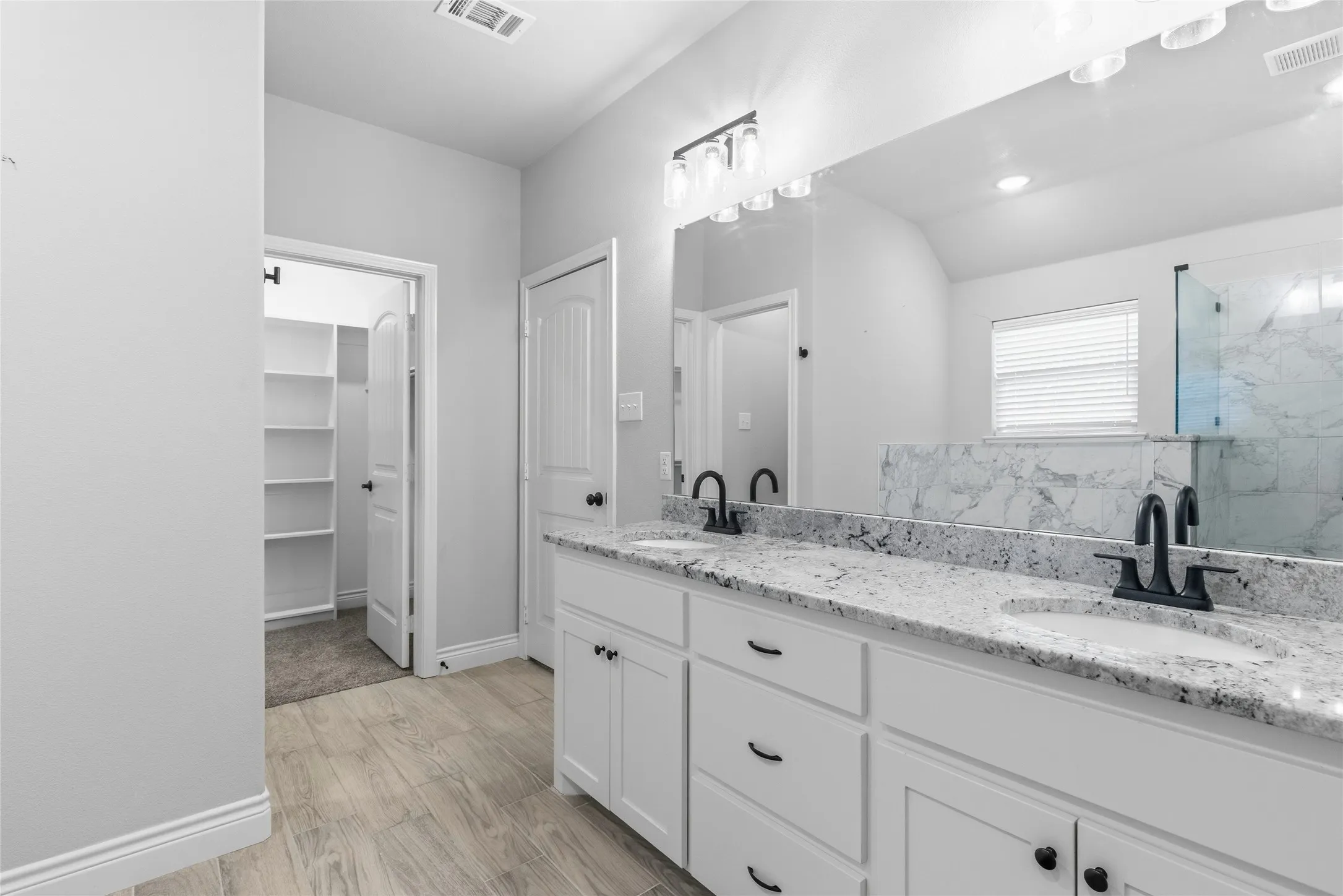 Dual vanity with granite countertops, undermount sinks, and matte black hardware