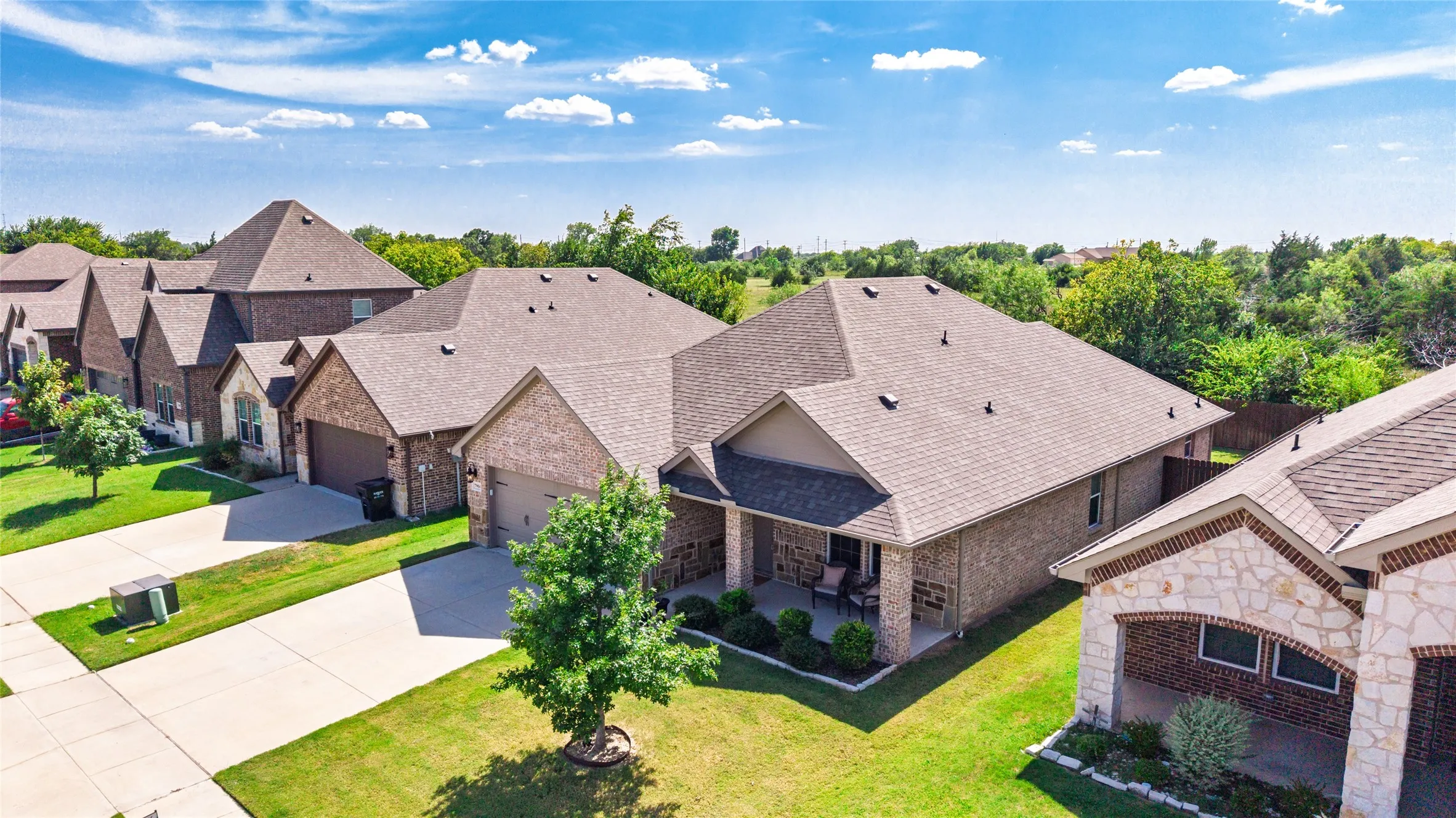 Brick exterior with a covered porch, two-car garage, and landscaped front yard