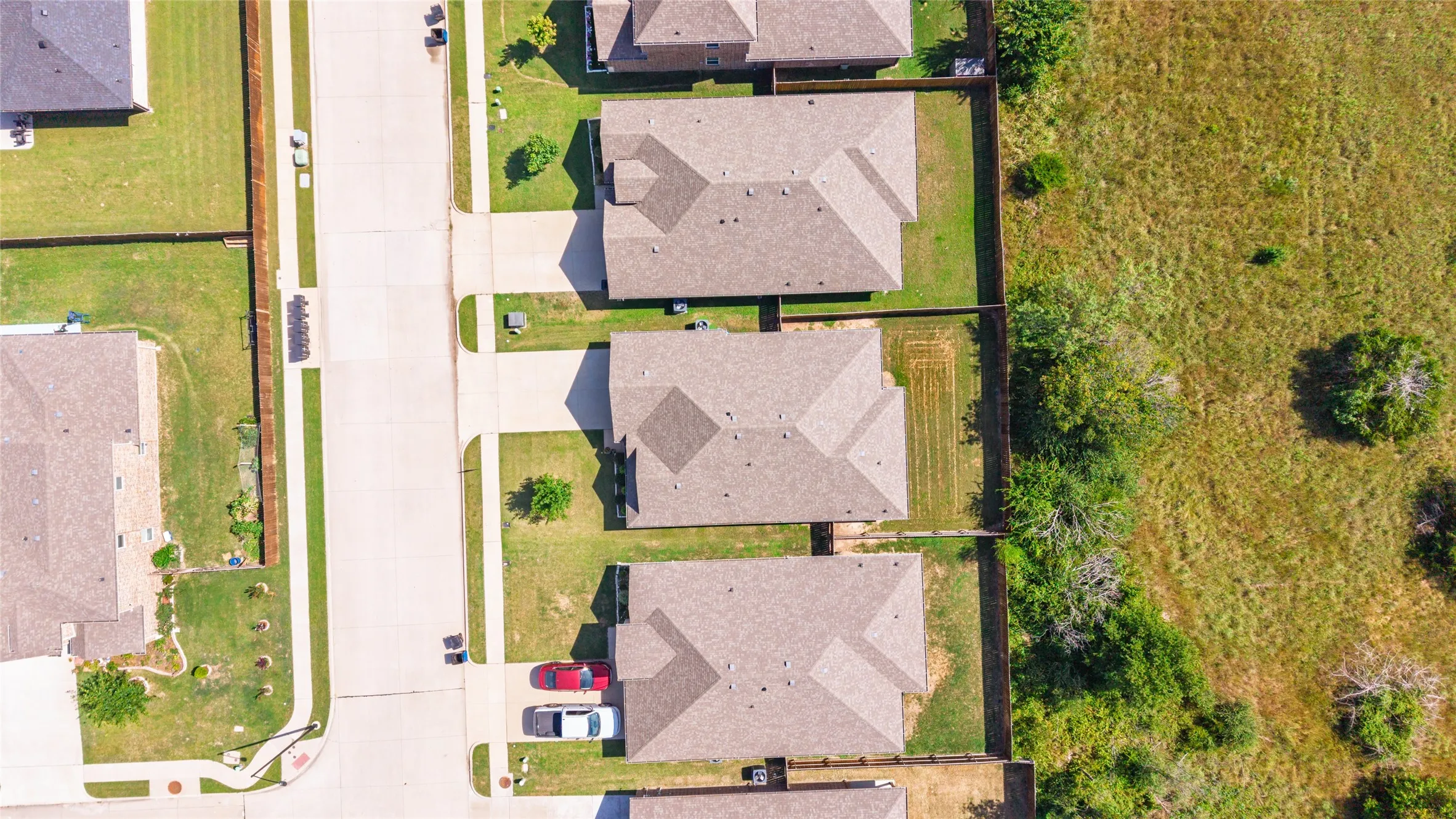 Residential street featuring multiple properties with uniform rooflines and fenced backyards