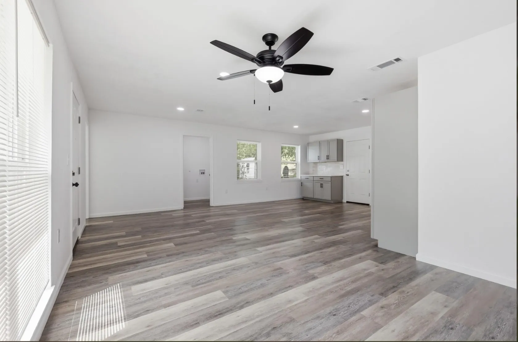 Spacious room featuring wood-finish flooring, recessed lighting, and a contemporary ceiling fan