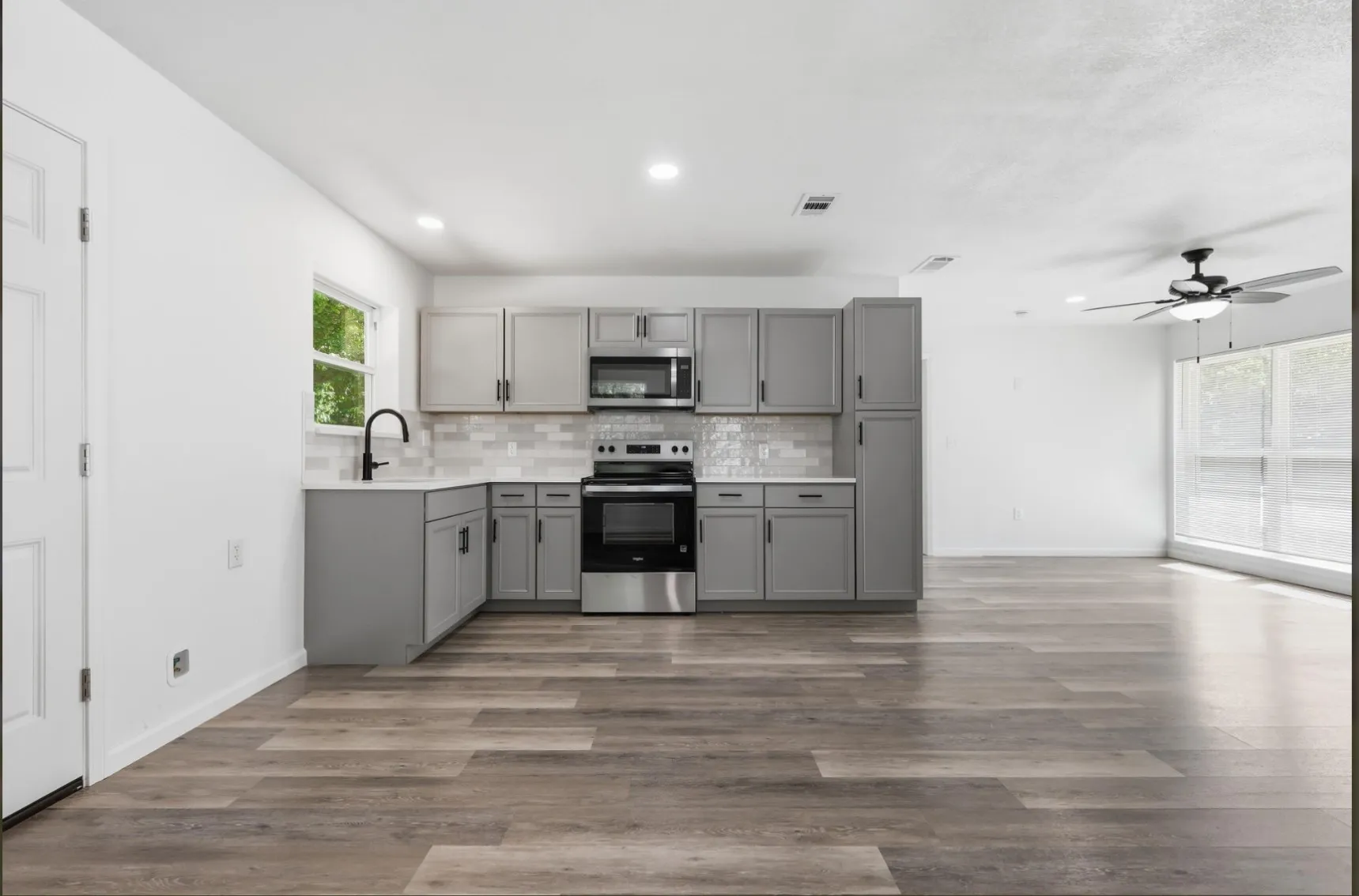 Modern kitchen featuring gray cabinetry, stainless steel appliances, and a white subway tile backsplash