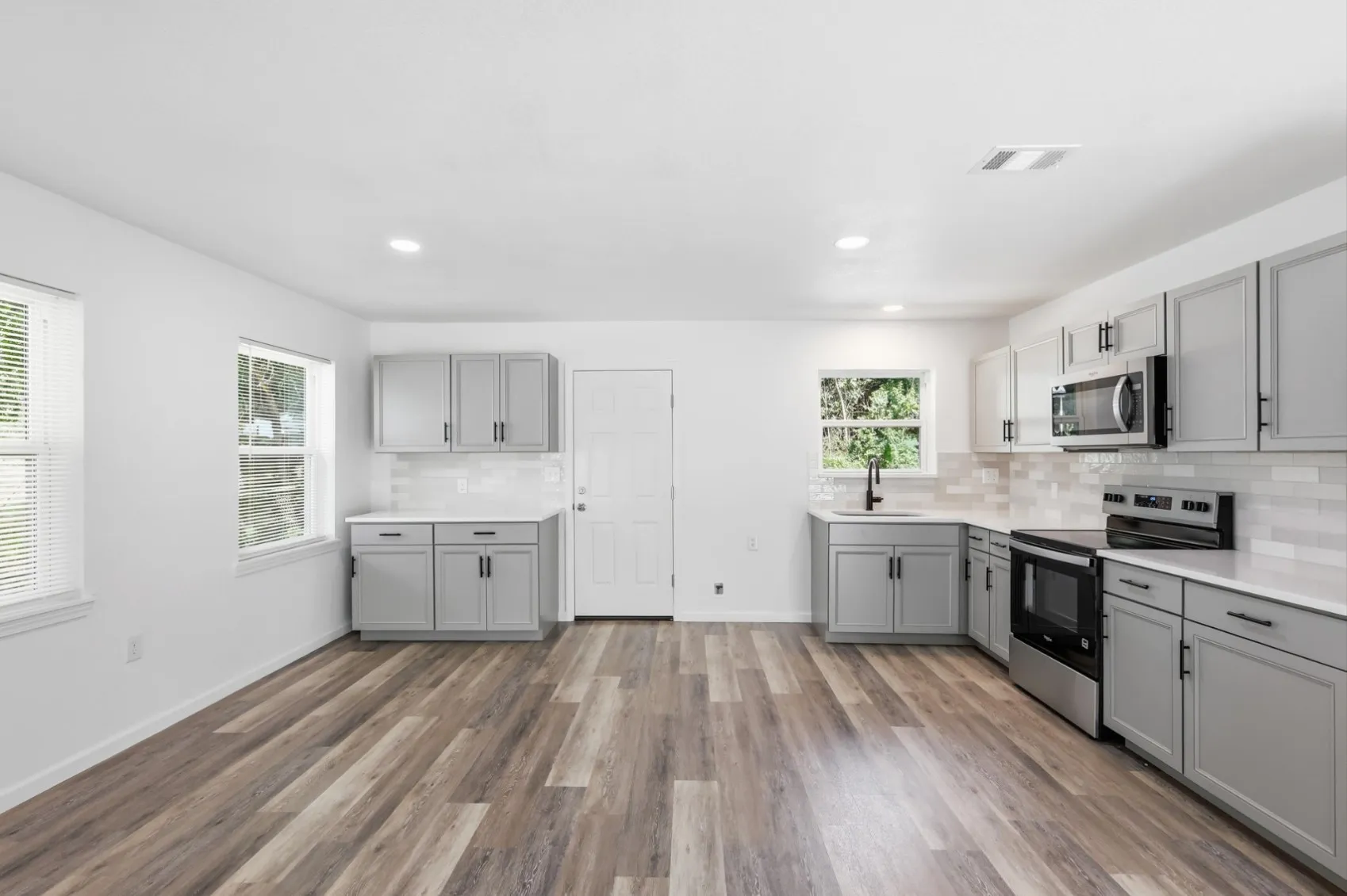 Spacious kitchen featuring wood-finish flooring, white walls, and recessed lighting