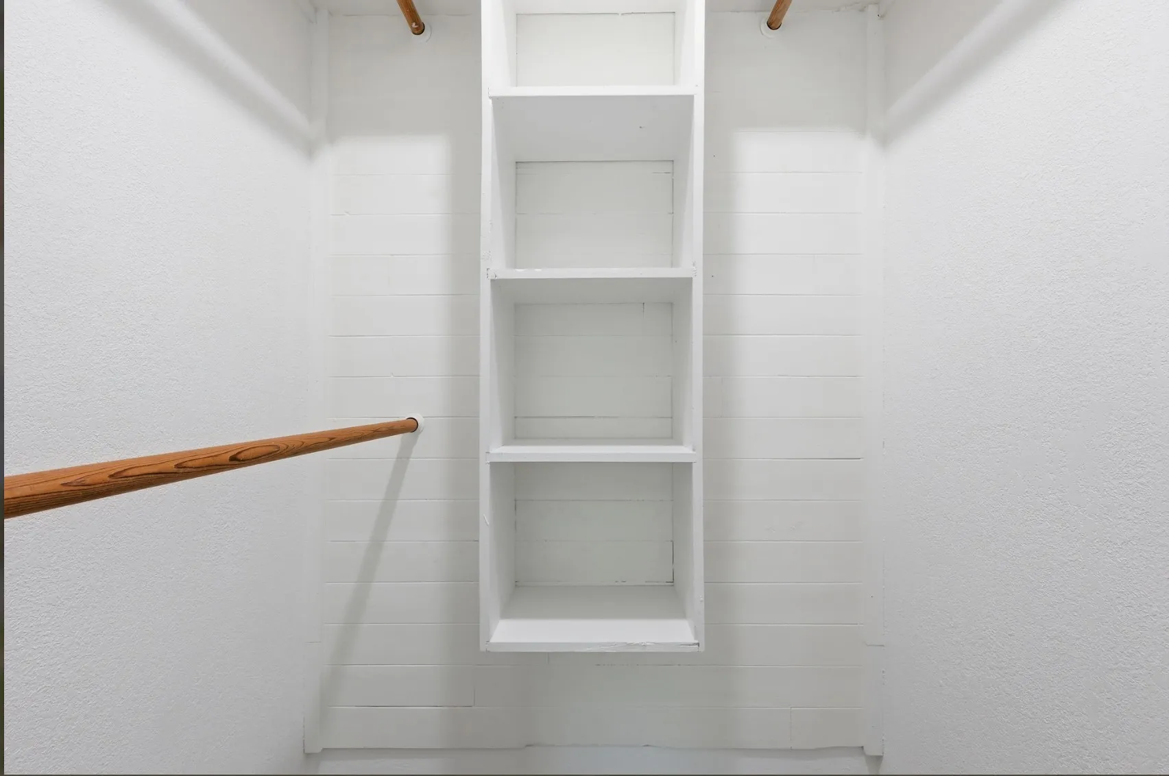 Walk-in closet featuring built-in shelving, dual hanging rods, and white painted walls