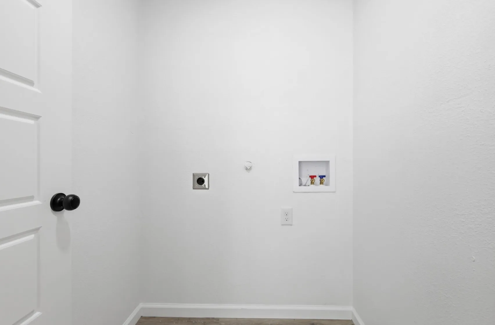 Dedicated utility area featuring white walls, baseboard trim, and a paneled door with a black knob