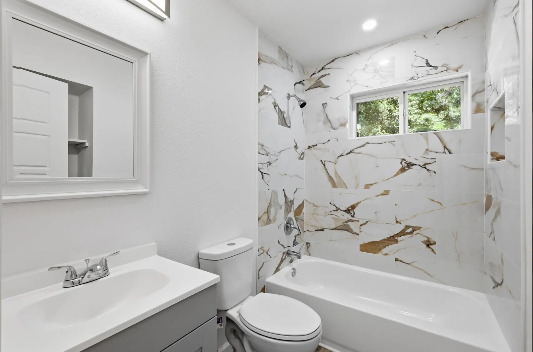 Bathroom featuring a single-basin vanity with a light gray cabinet, a framed mirror, and chrome fixtures