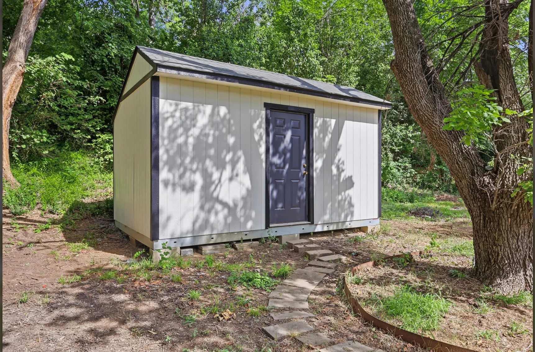 Detached storage shed with a dark gray door and black trim